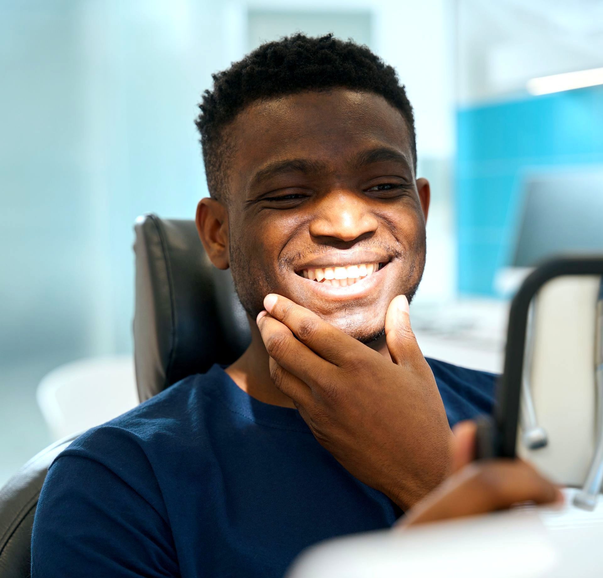 A man is smiling while looking at his teeth in a mirror.