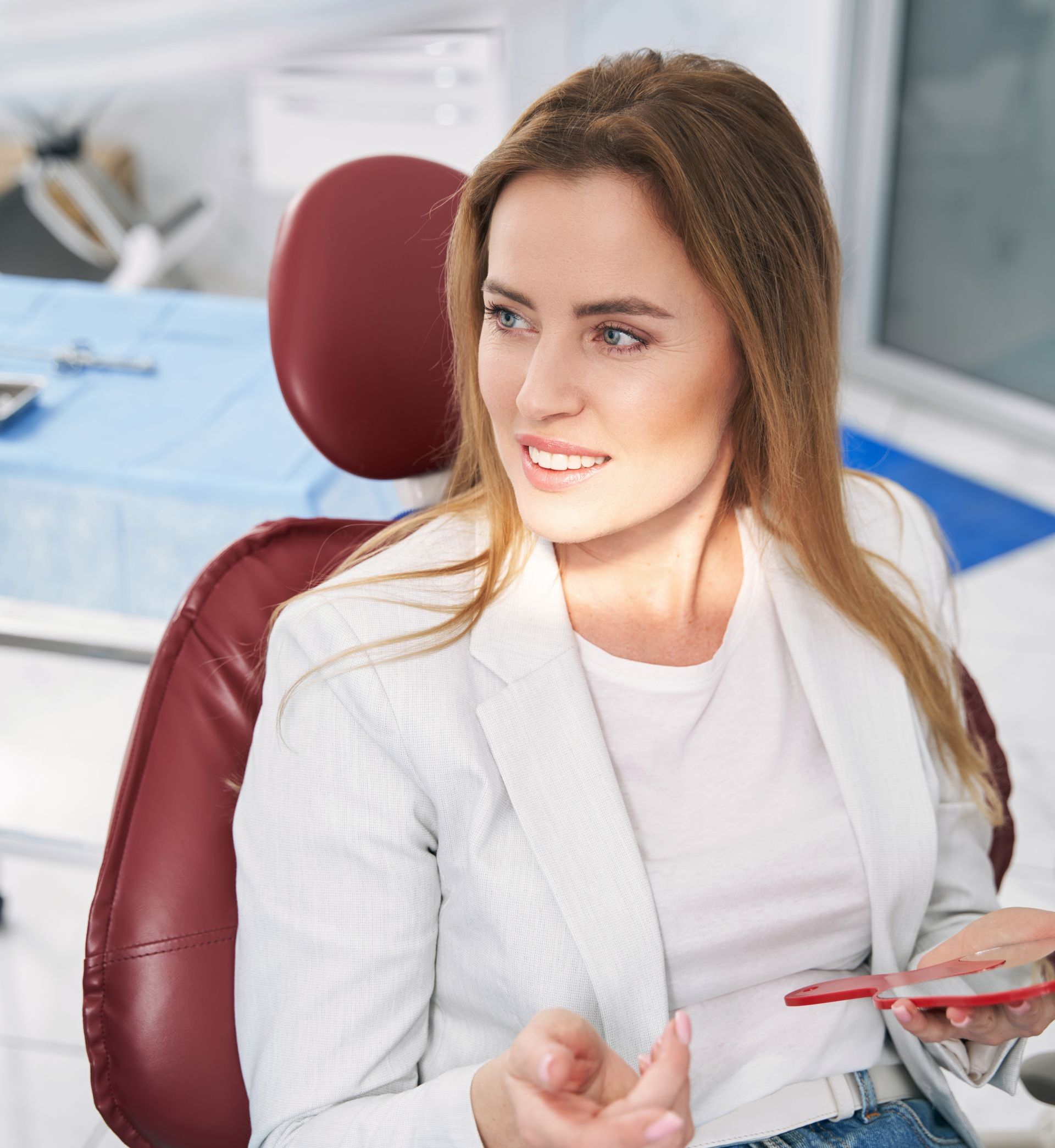 A woman is sitting in a dental chair holding a cell phone.