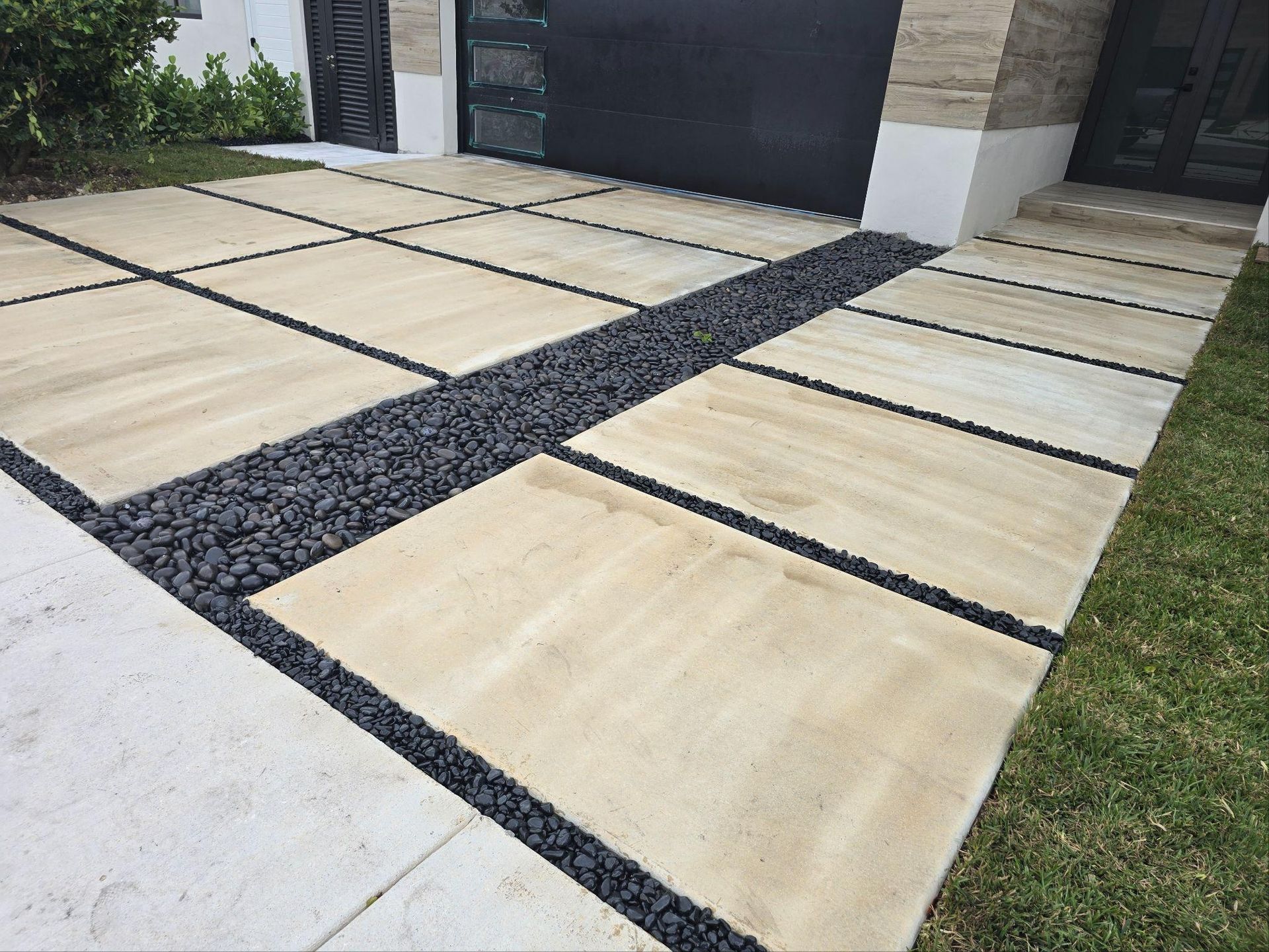 A driveway with a brick walkway and a lawn in front of a house.