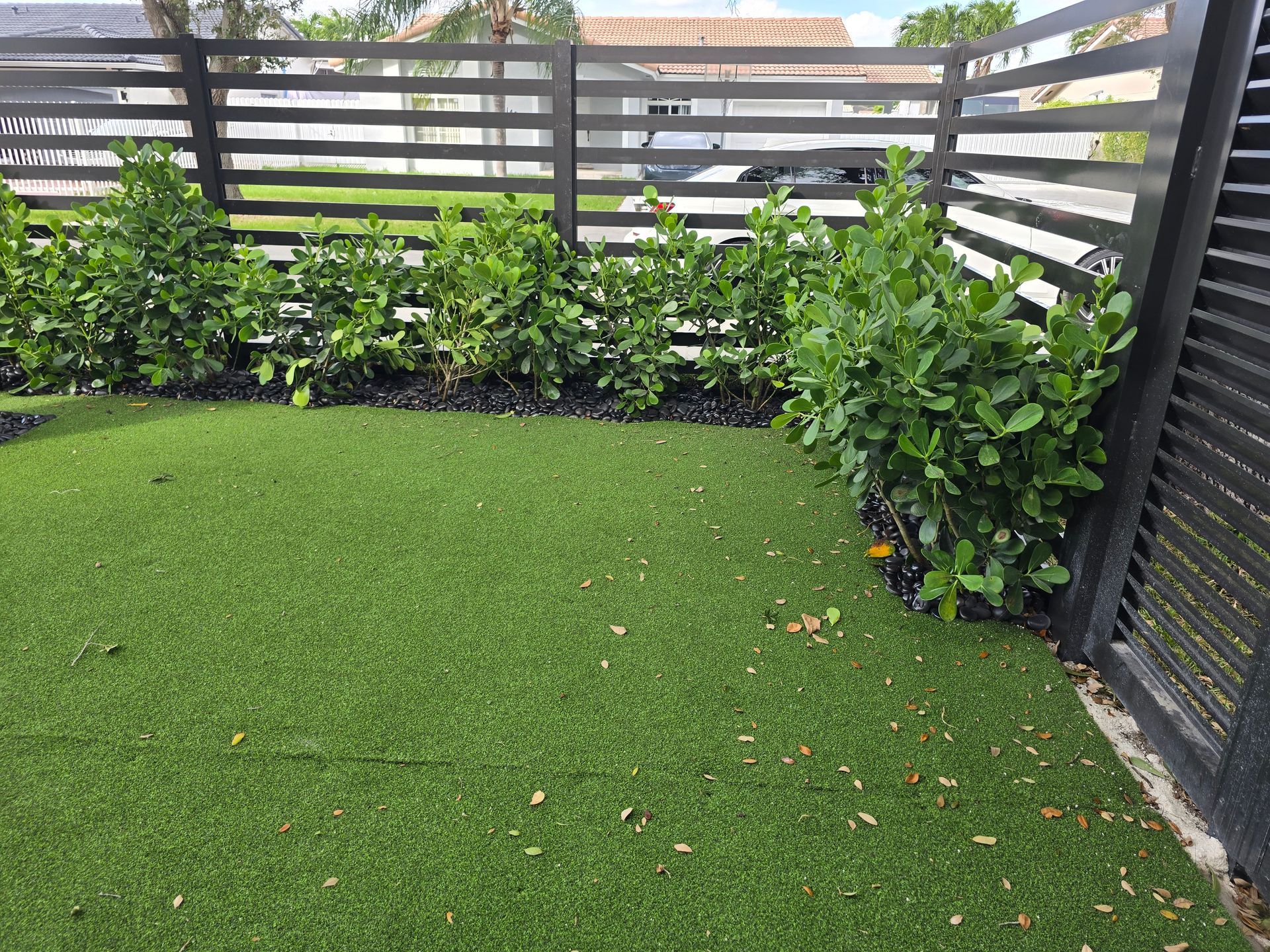A backyard with a fence and a lush green lawn.