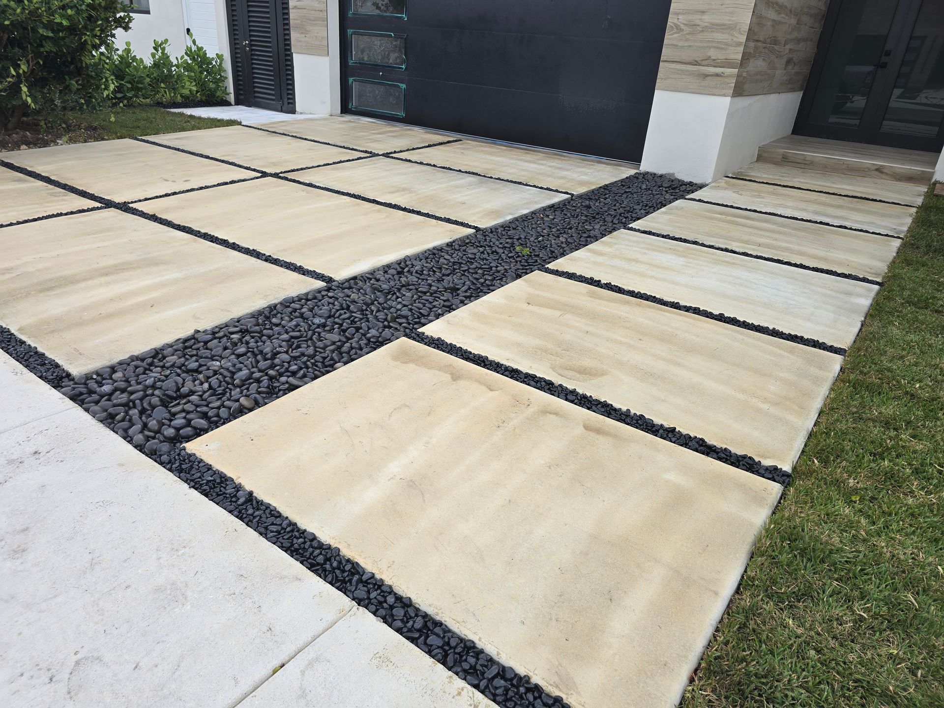 A driveway with tiles and gravel in front of a house.