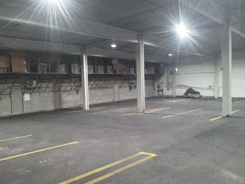 Empty, indoor parking garage with bright overhead lights and yellow parking lines.