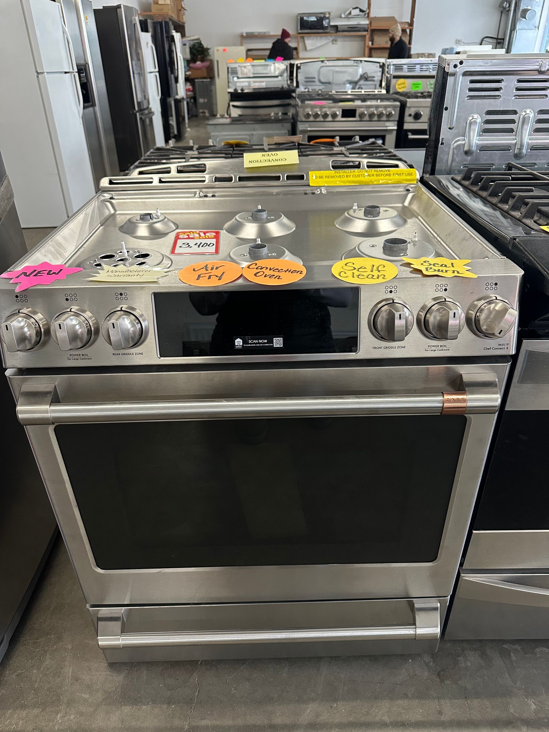 Stainless steel range with stovetop burners and oven. Appliance store setting.