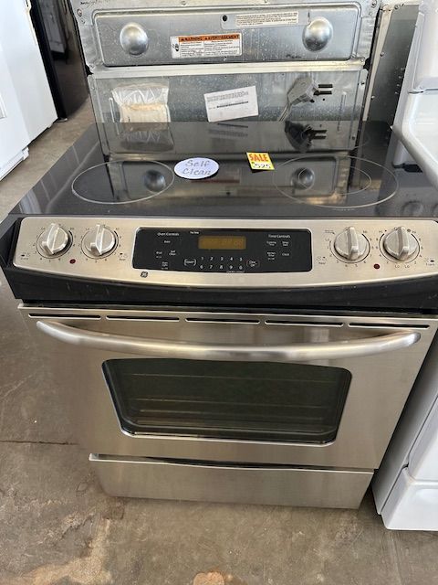 A stainless steel stove top oven is sitting on a concrete floor.