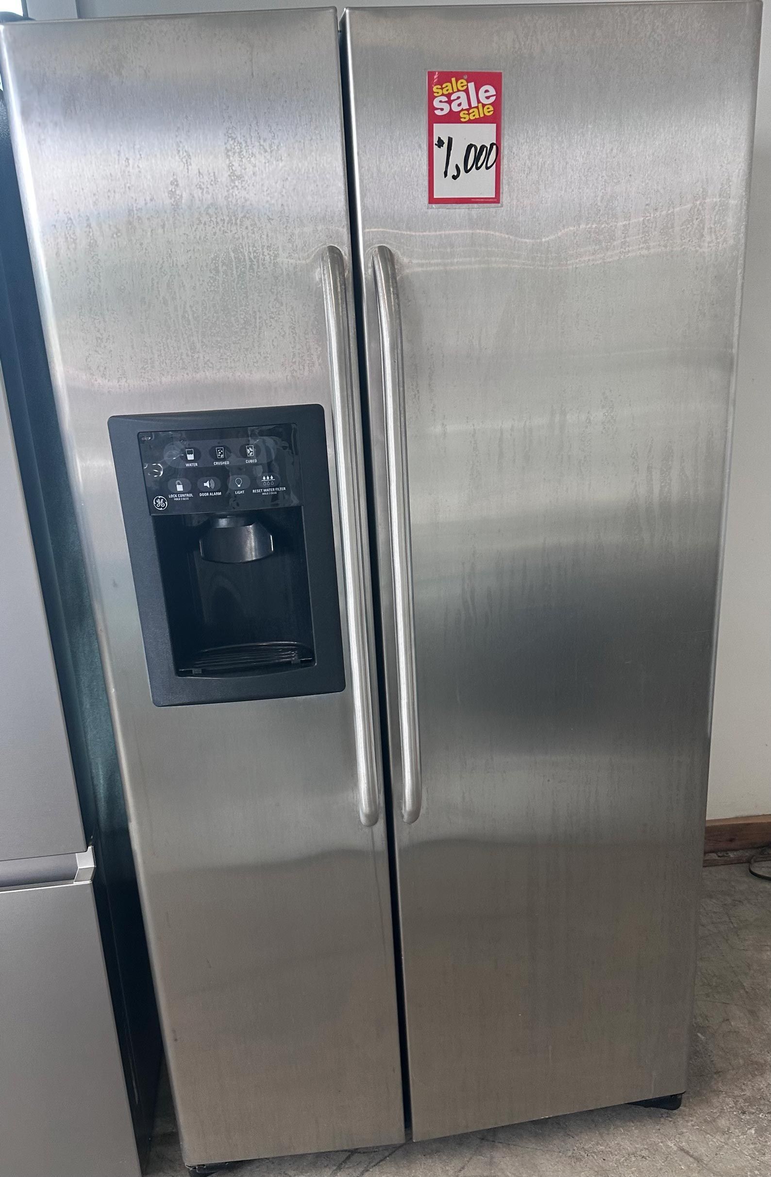 A stainless steel refrigerator with a water dispenser is sitting on the floor.