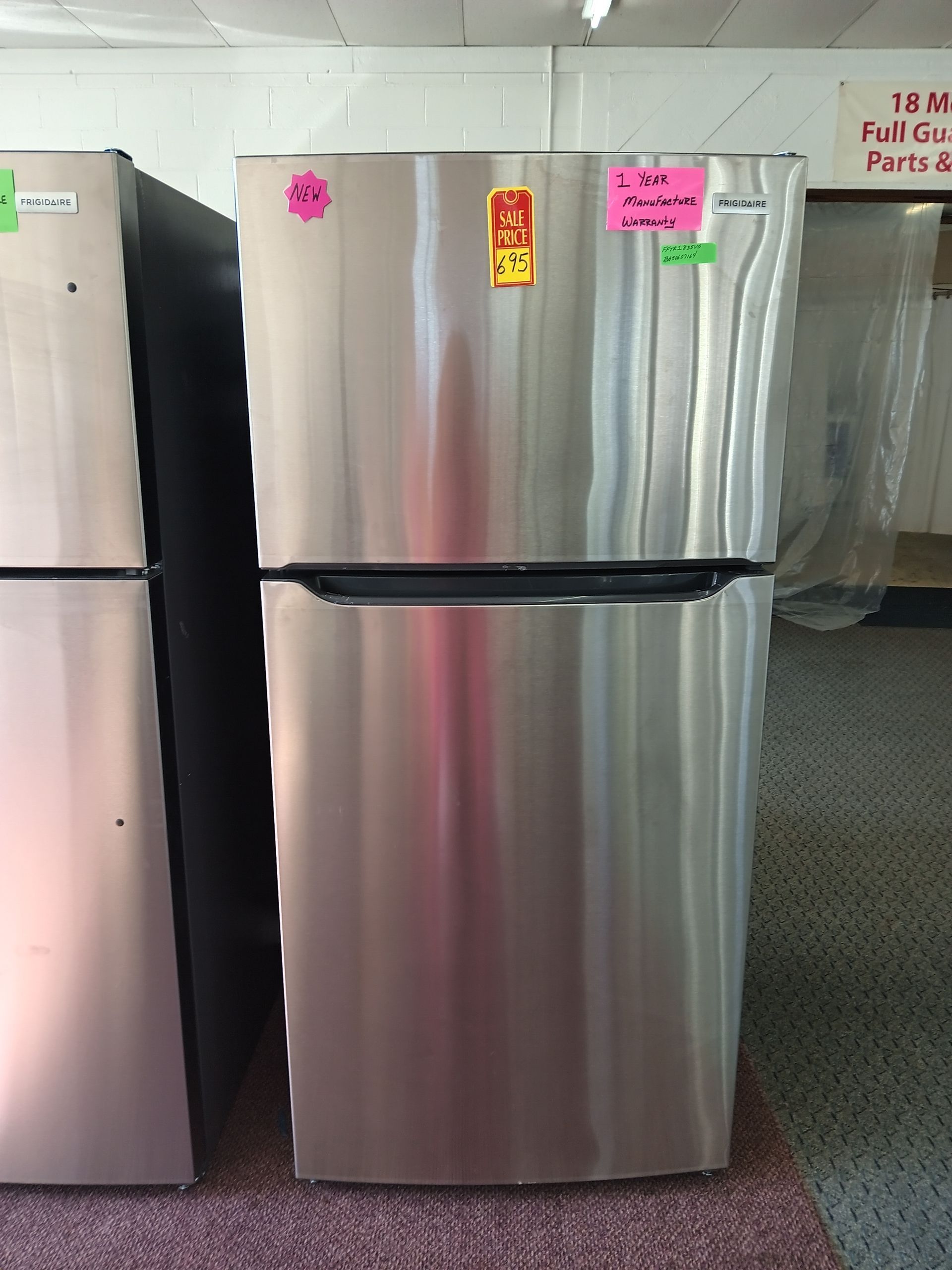 Side-by-side stainless steel refrigerator with a water/ice dispenser. It stands in front of a window.