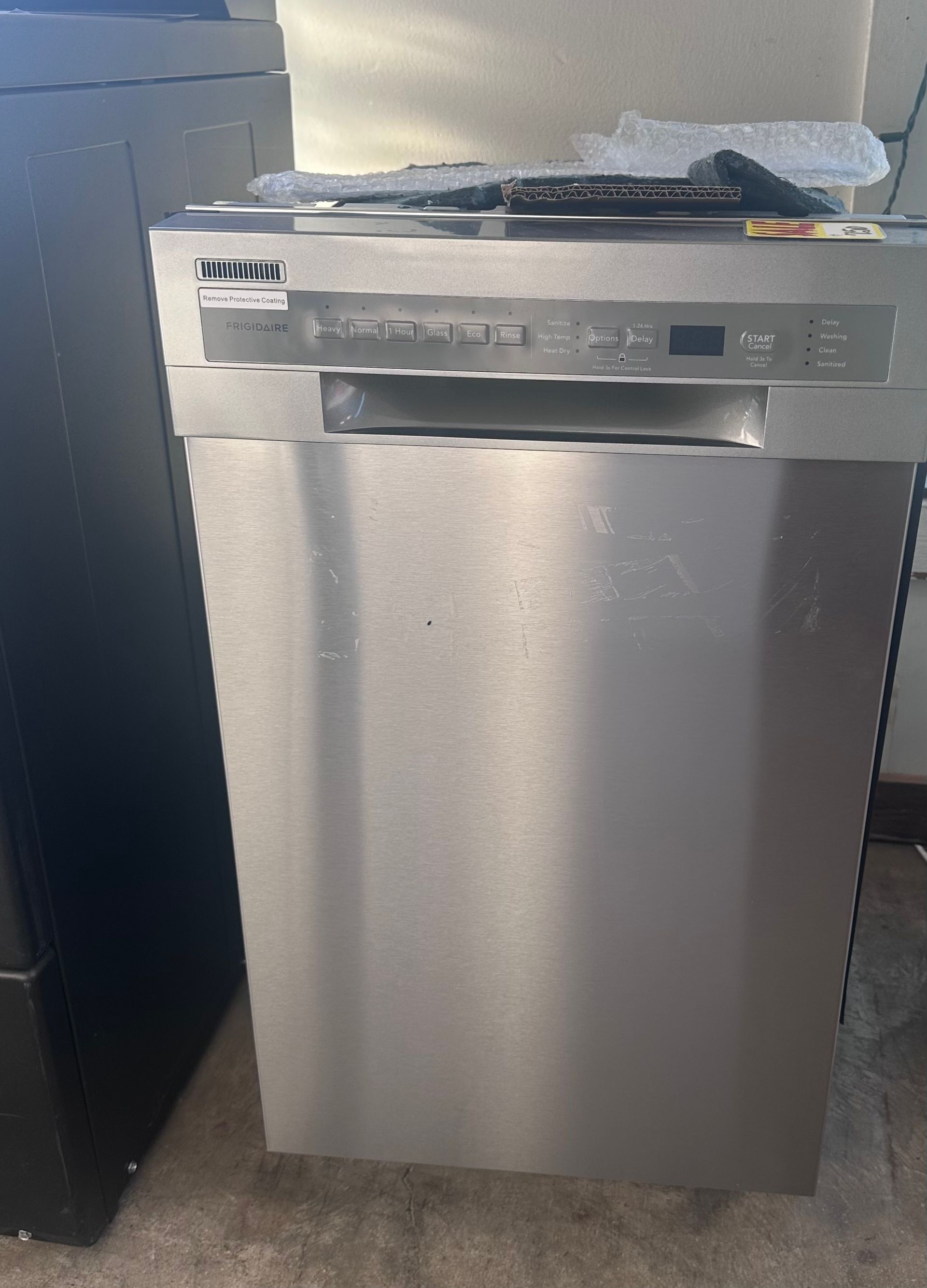 Stainless steel dishwasher with control panel and door in a kitchen setting.