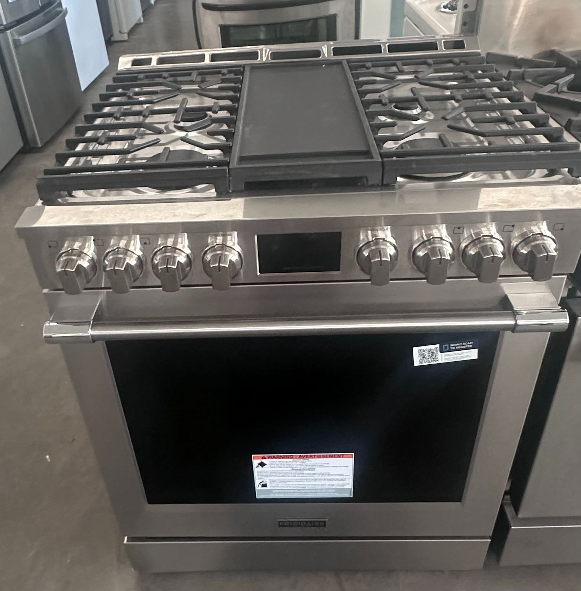 Stainless steel gas range with black cooktop and oven door.