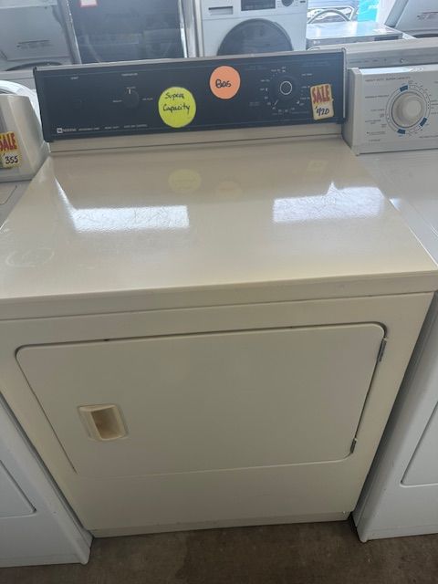 A white dryer is sitting on top of a counter in a laundry room.
