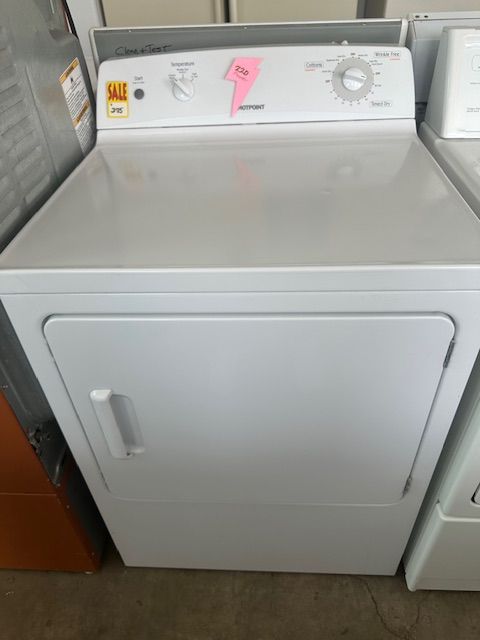A white dryer is sitting next to a washer and dryer.
