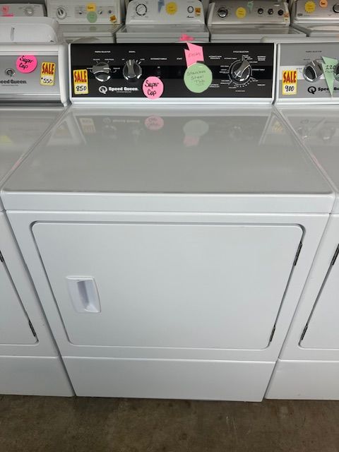 A white dryer is sitting in a laundromat