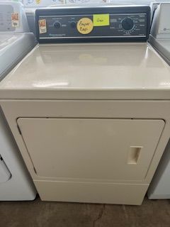 A white dryer is sitting on top of a concrete floor next to a washer and dryer.