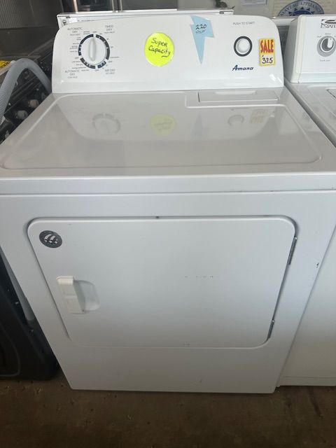 A white washer and dryer are sitting on a wooden floor.