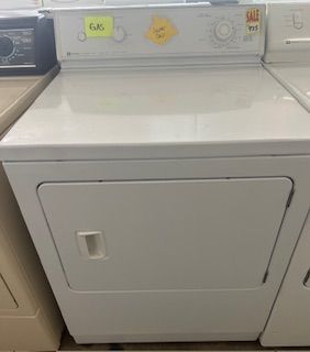 A white dryer is sitting on top of a counter next to a washer and dryer.