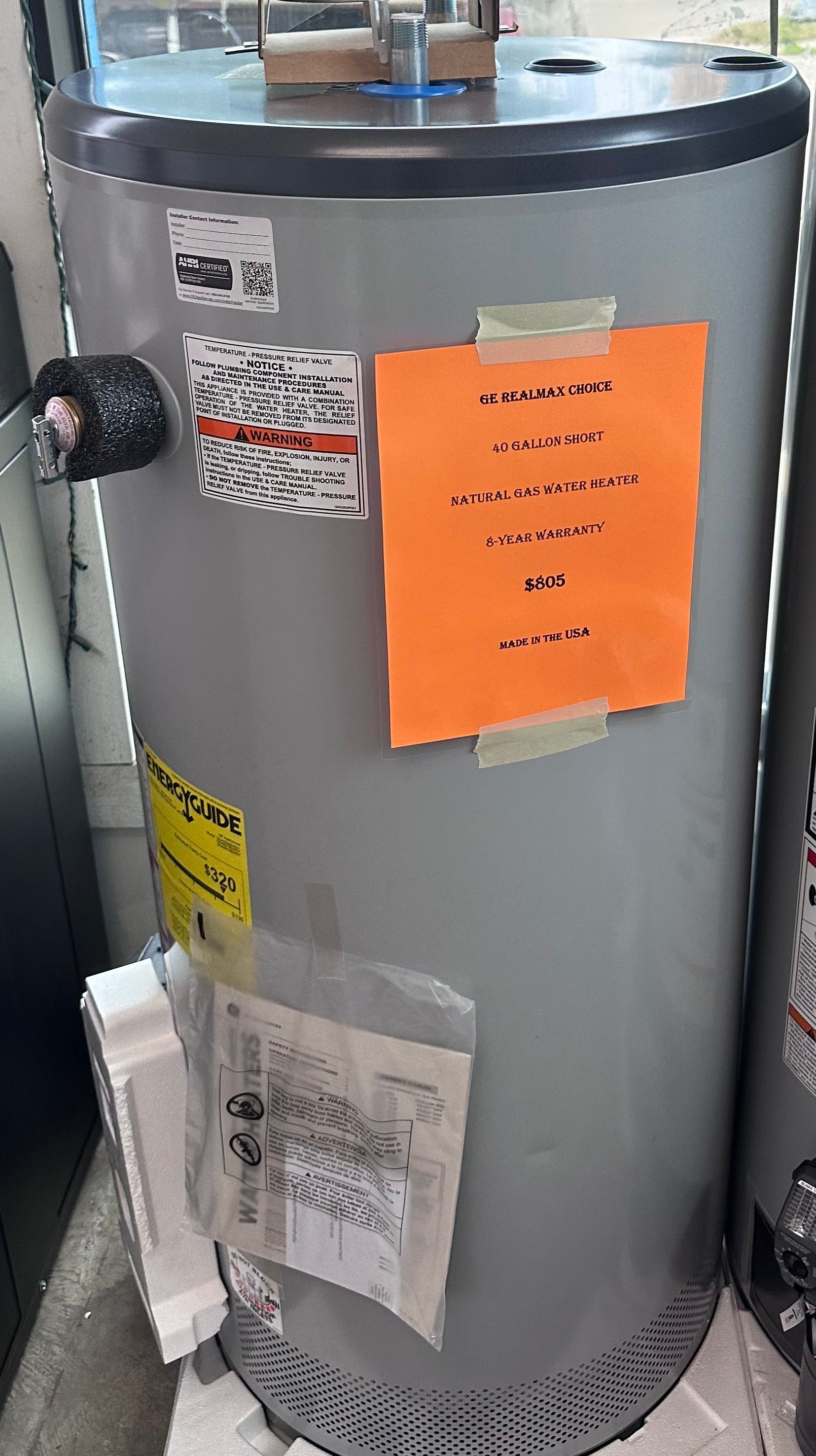 A water heater is sitting on top of a table with a sign taped to it.