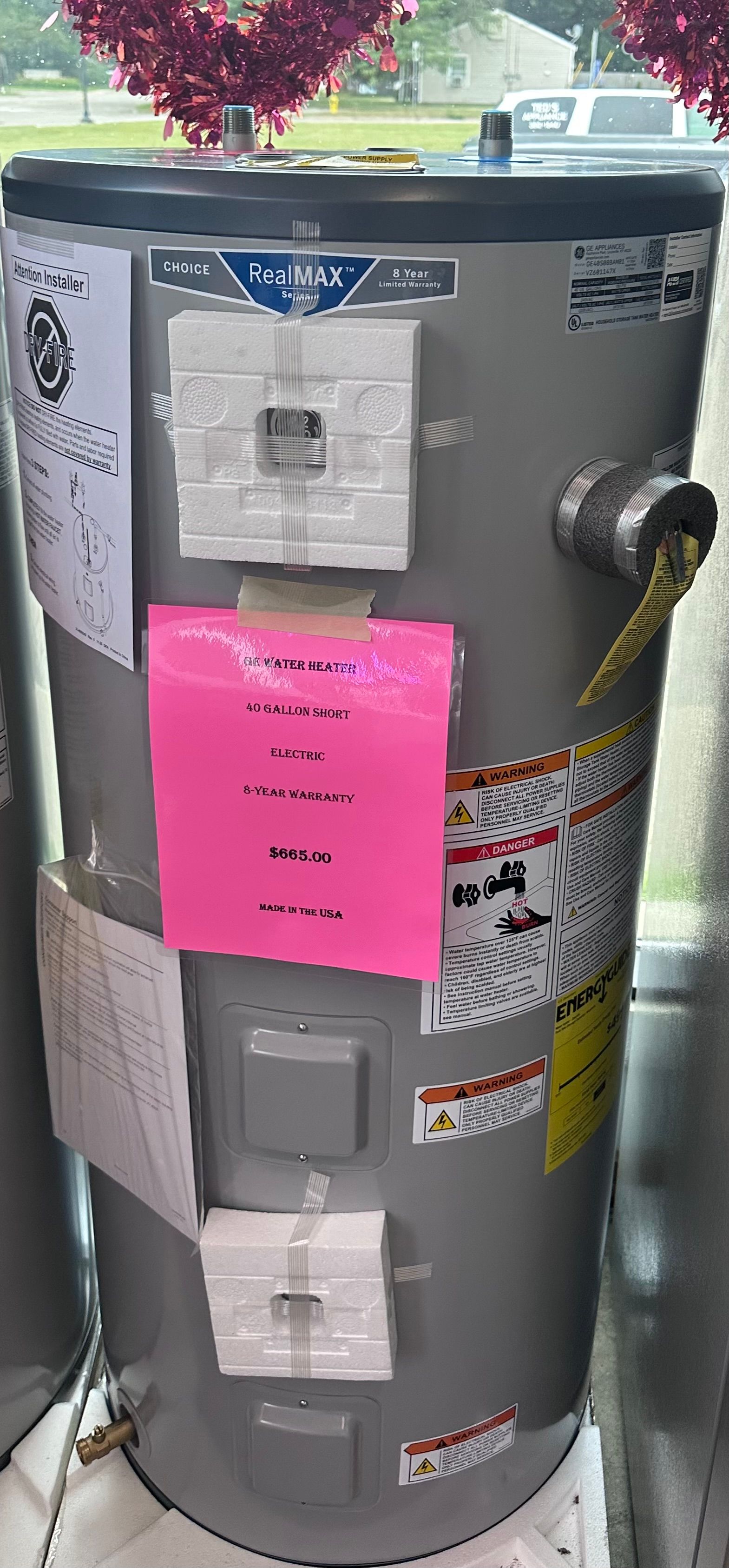 A water heater with a lot of stickers on it is sitting on a table.