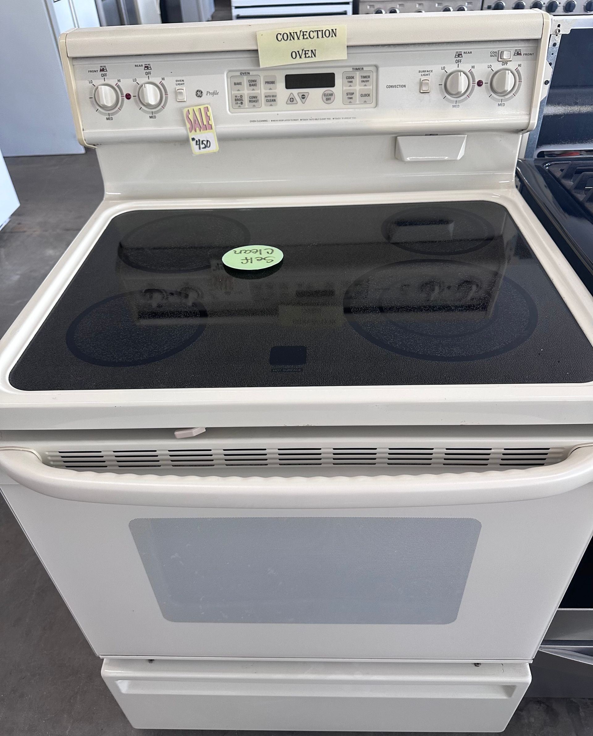 White electric stove with black cooktop, controls, and oven door, inside a store.