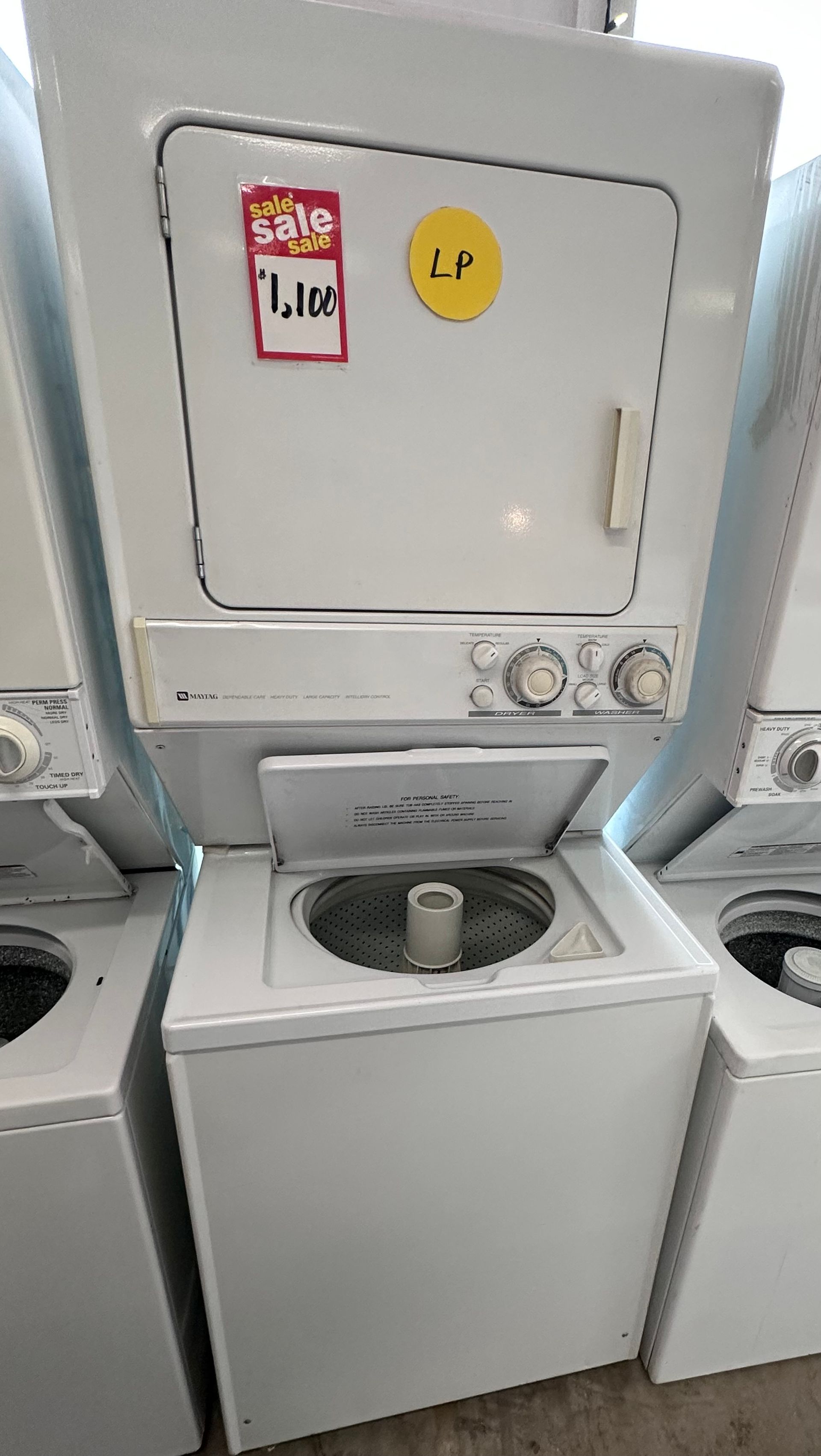 Stacked white washer and dryer, open washing machine lid, sale tag.