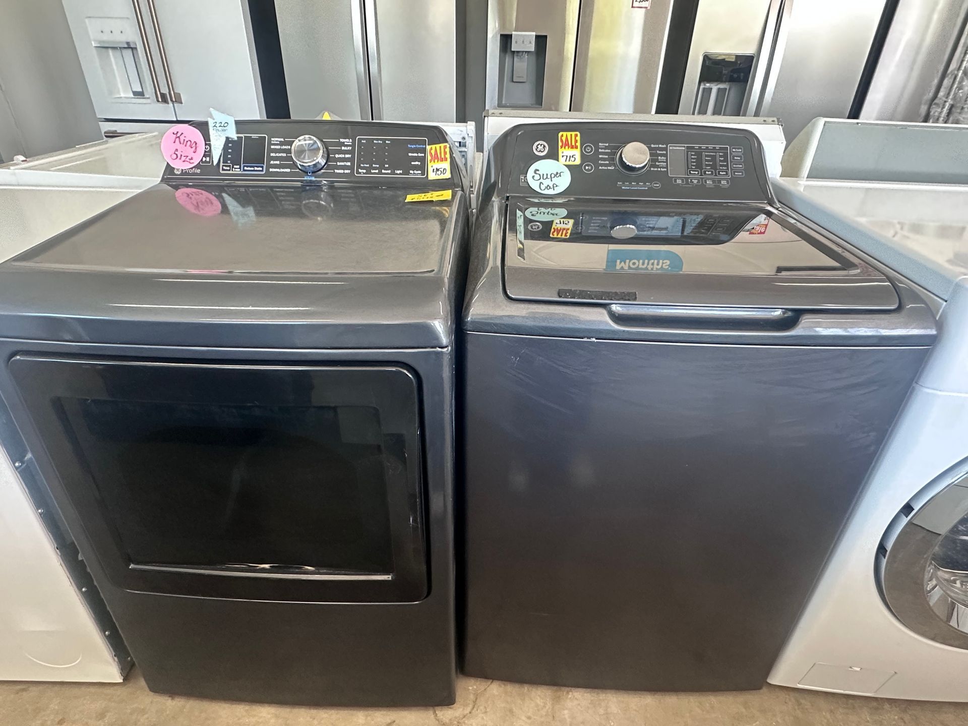 A white washing machine with the lid open is sitting next to another washing machine.