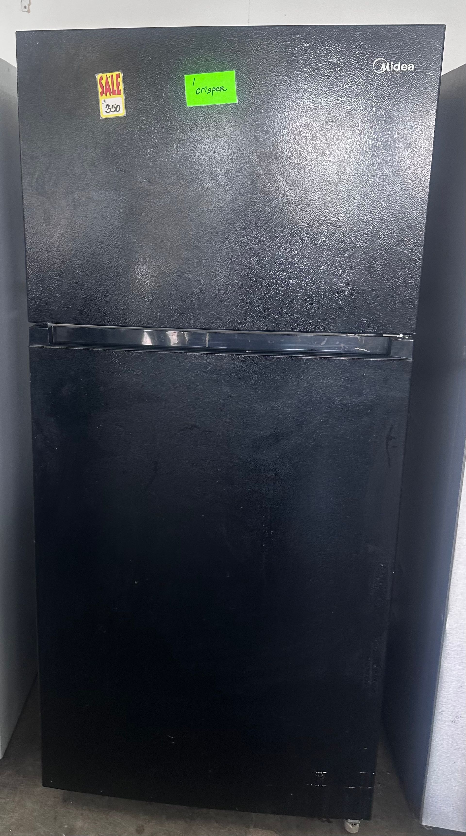 Black refrigerator standing against a wall, with two small magnets near the top.