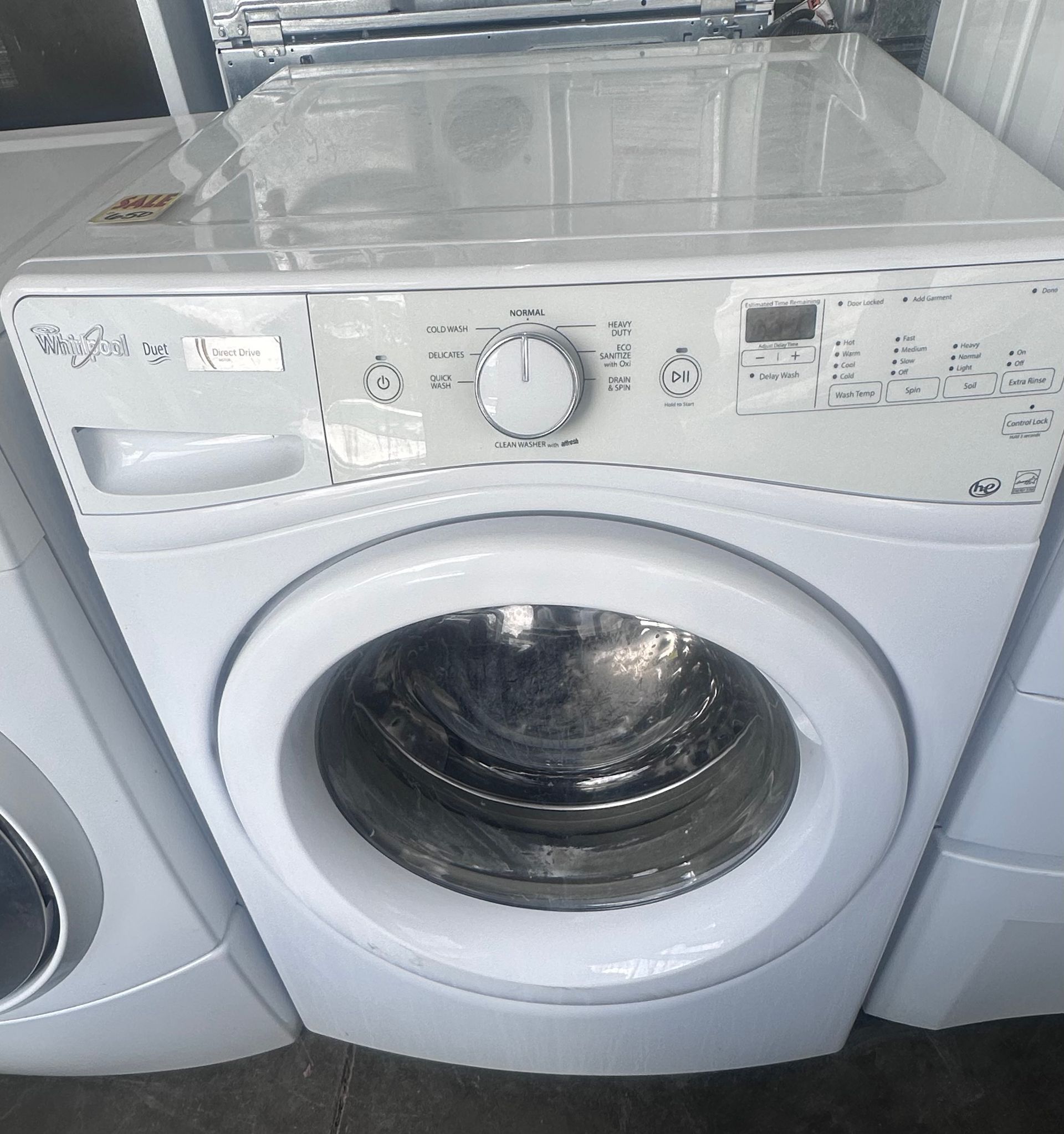 White front-loading washing machine with control dial and windowed door in a laundry appliance row