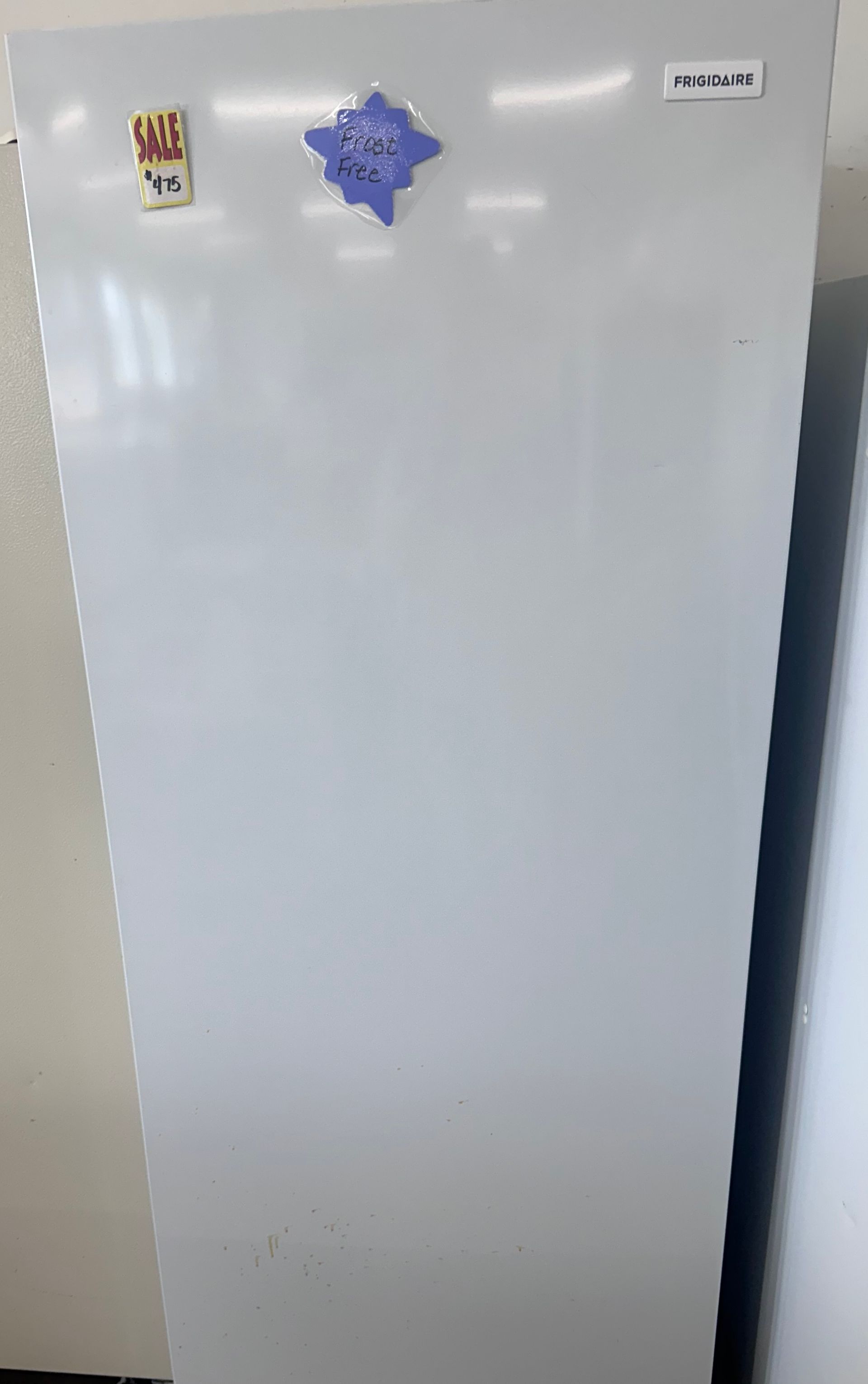 A white refrigerator with a purple sticker on the door.