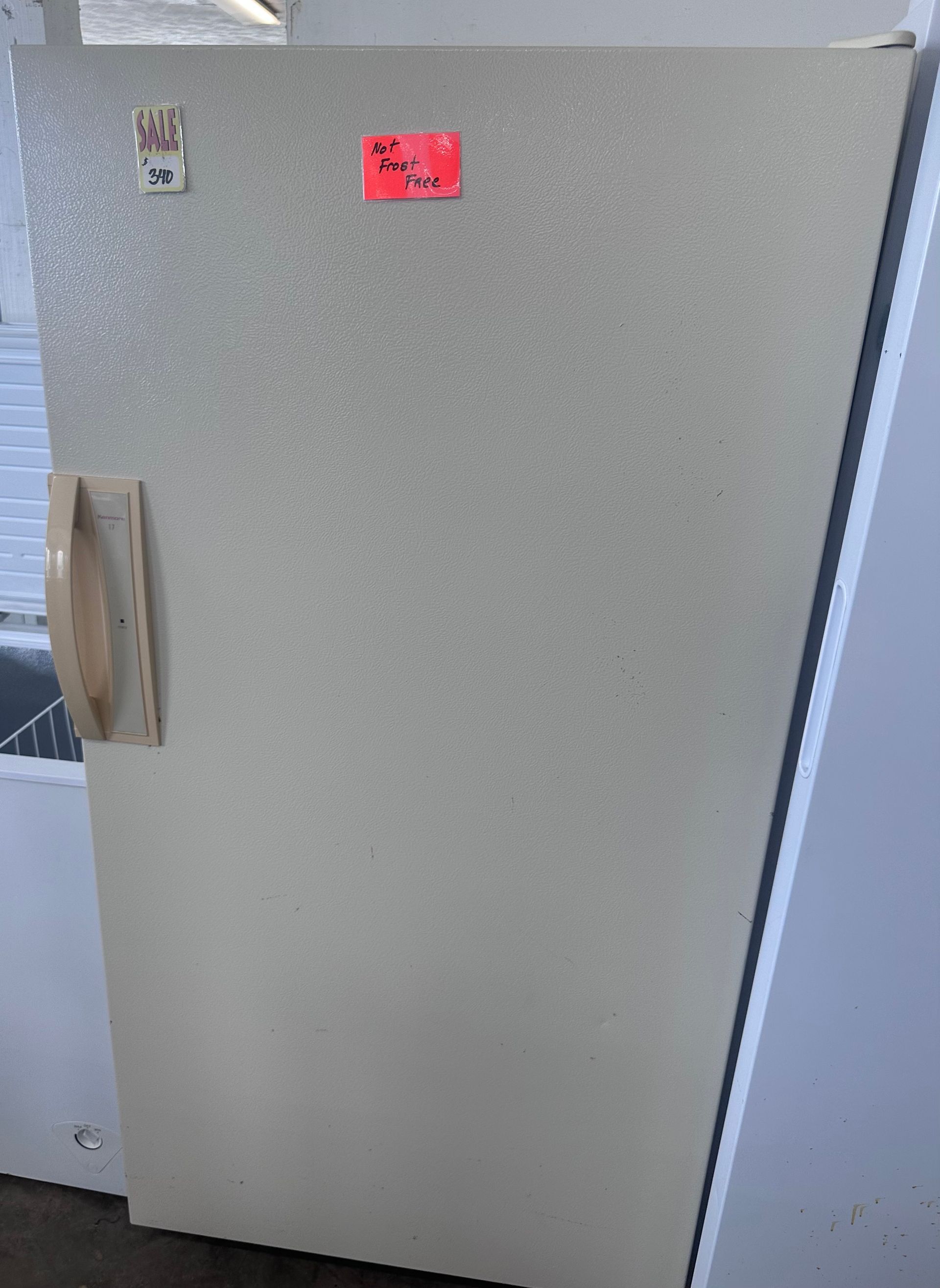 A white refrigerator with a red sticker on the door.