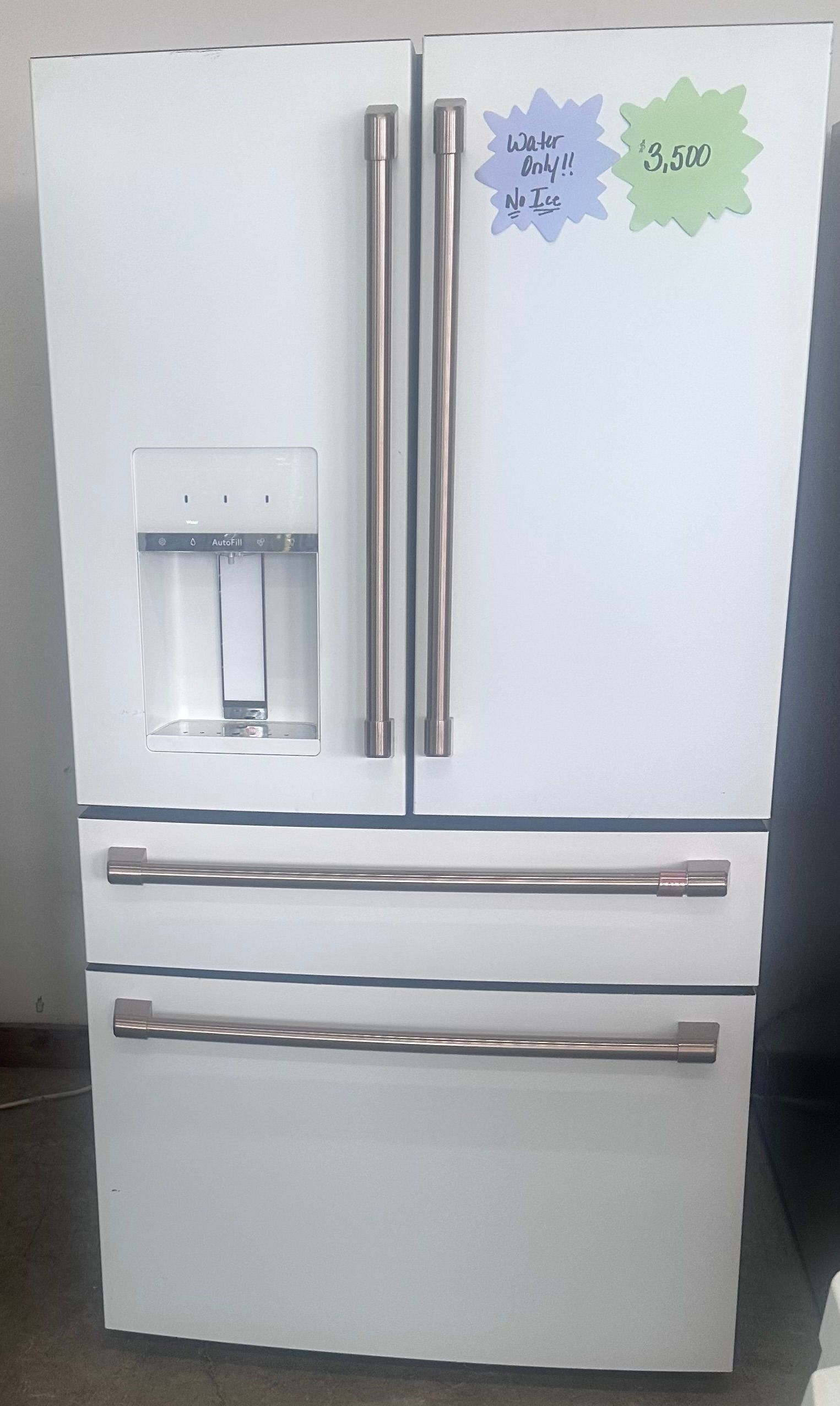 A stainless steel side-by-side refrigerator with a water dispenser, taped doors, and price labels attached.