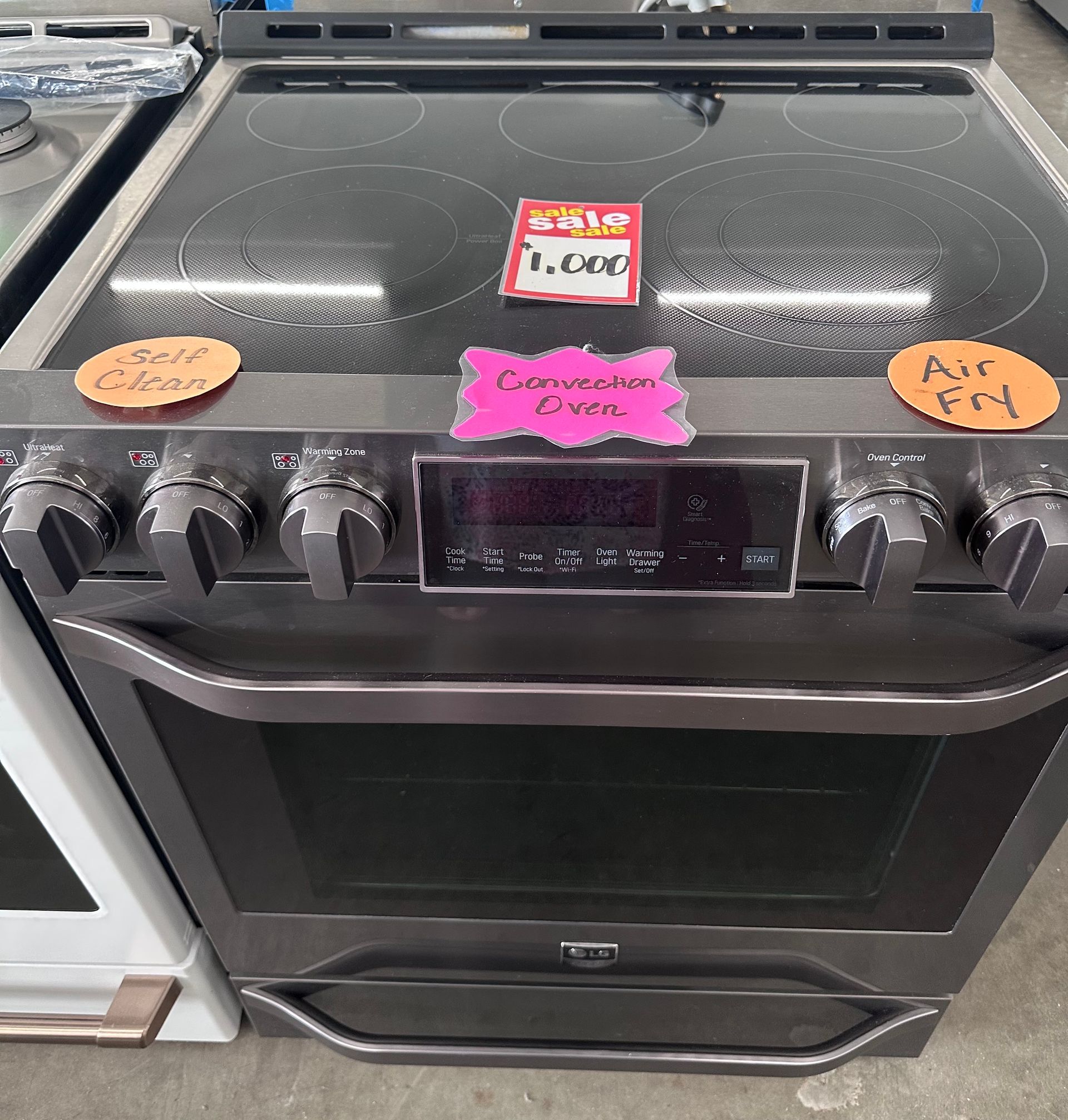 A stainless steel range with a glass cooktop, oven, and digital controls; labeled