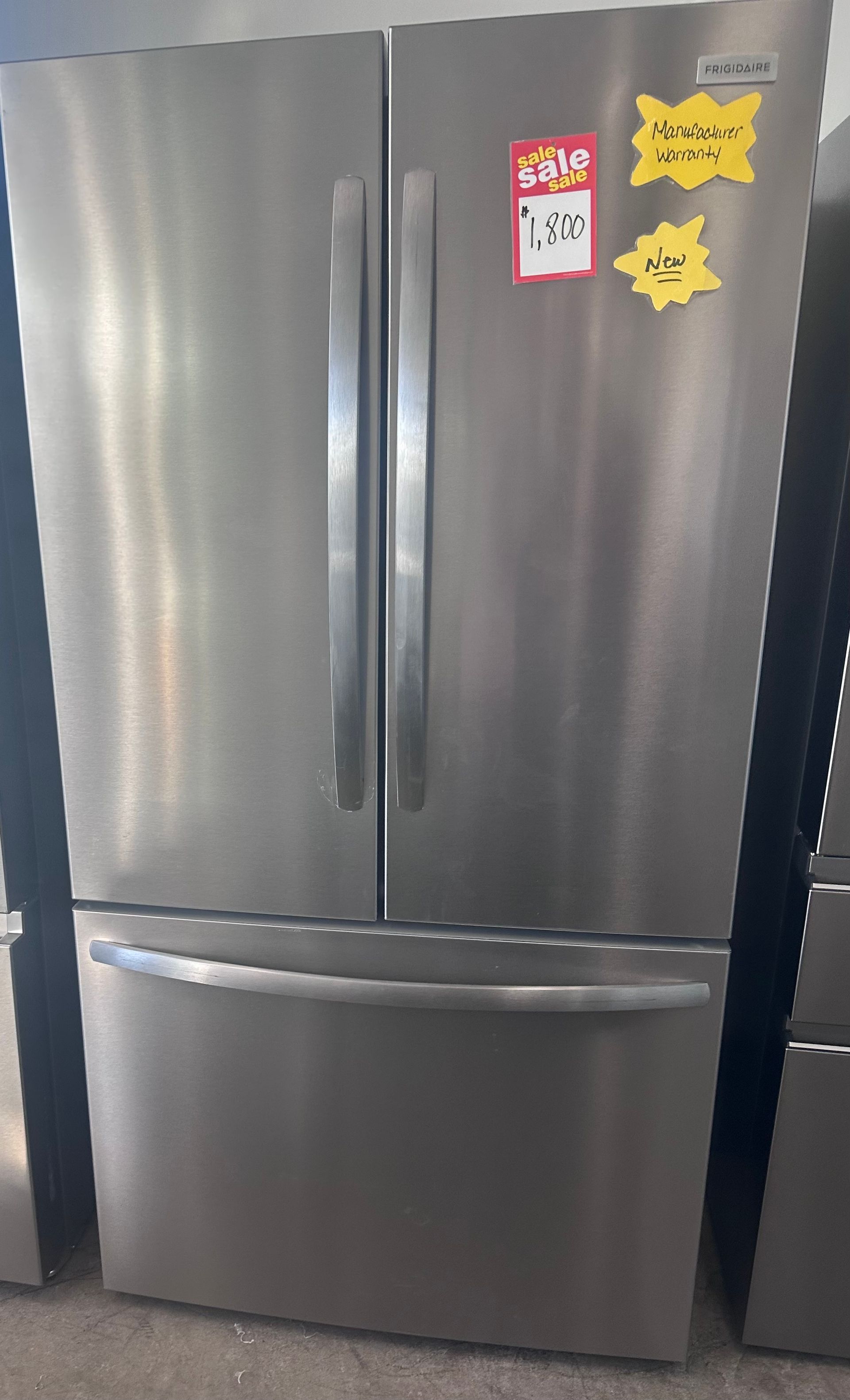 Stainless steel French door refrigerator with price tags.