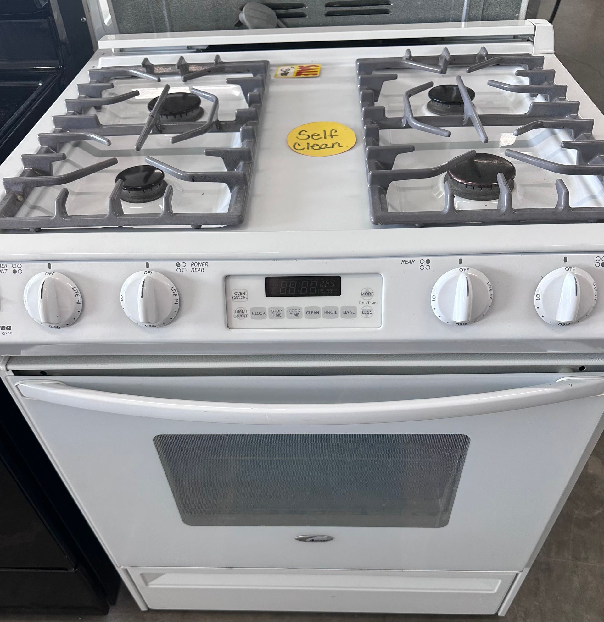 White gas range with four burners and a self-cleaning oven, knobs along the top.