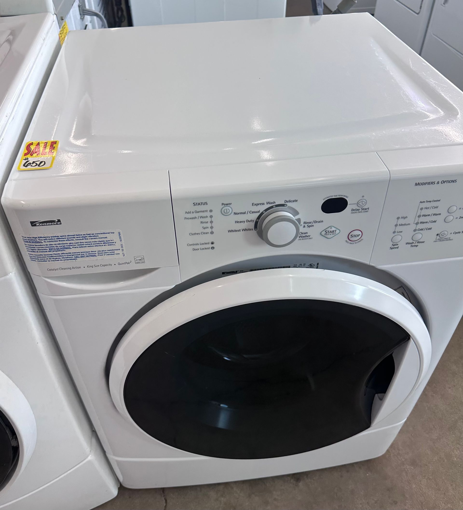 White front-load washing machine with a dark round door and control panel on top.
