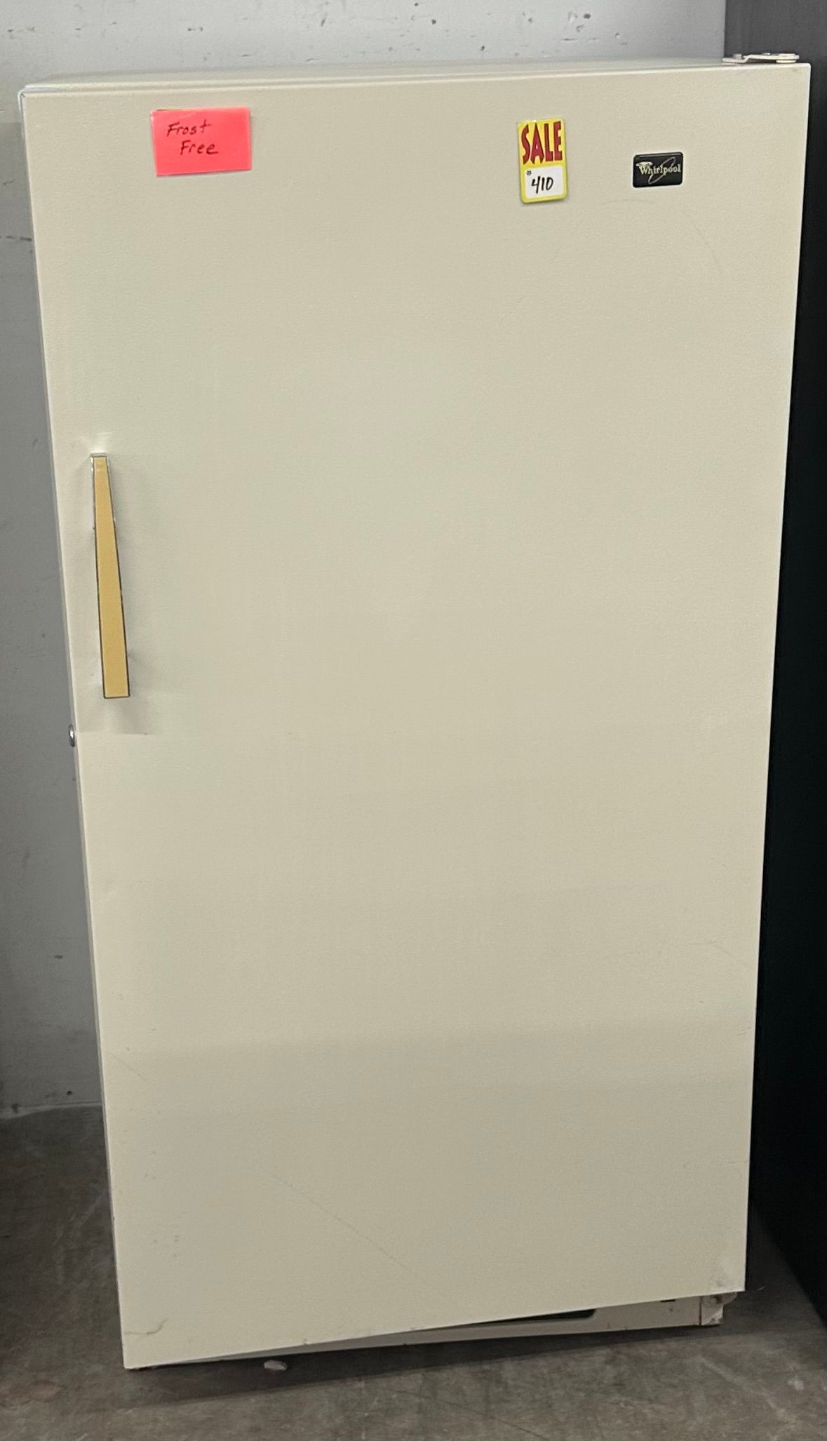 White refrigerator with a yellow handle and small magnets on the top front.