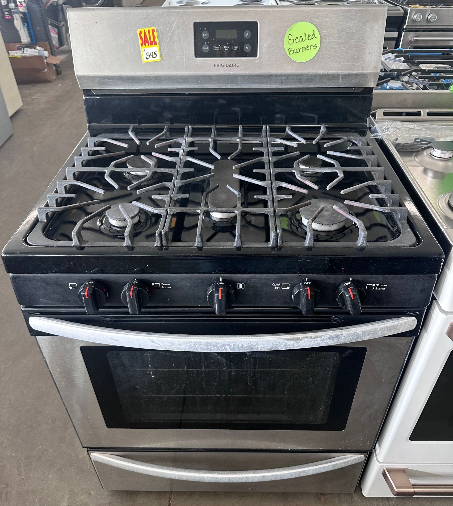 Stainless steel gas range with black cooktop and oven. Knobs and burner grates visible.