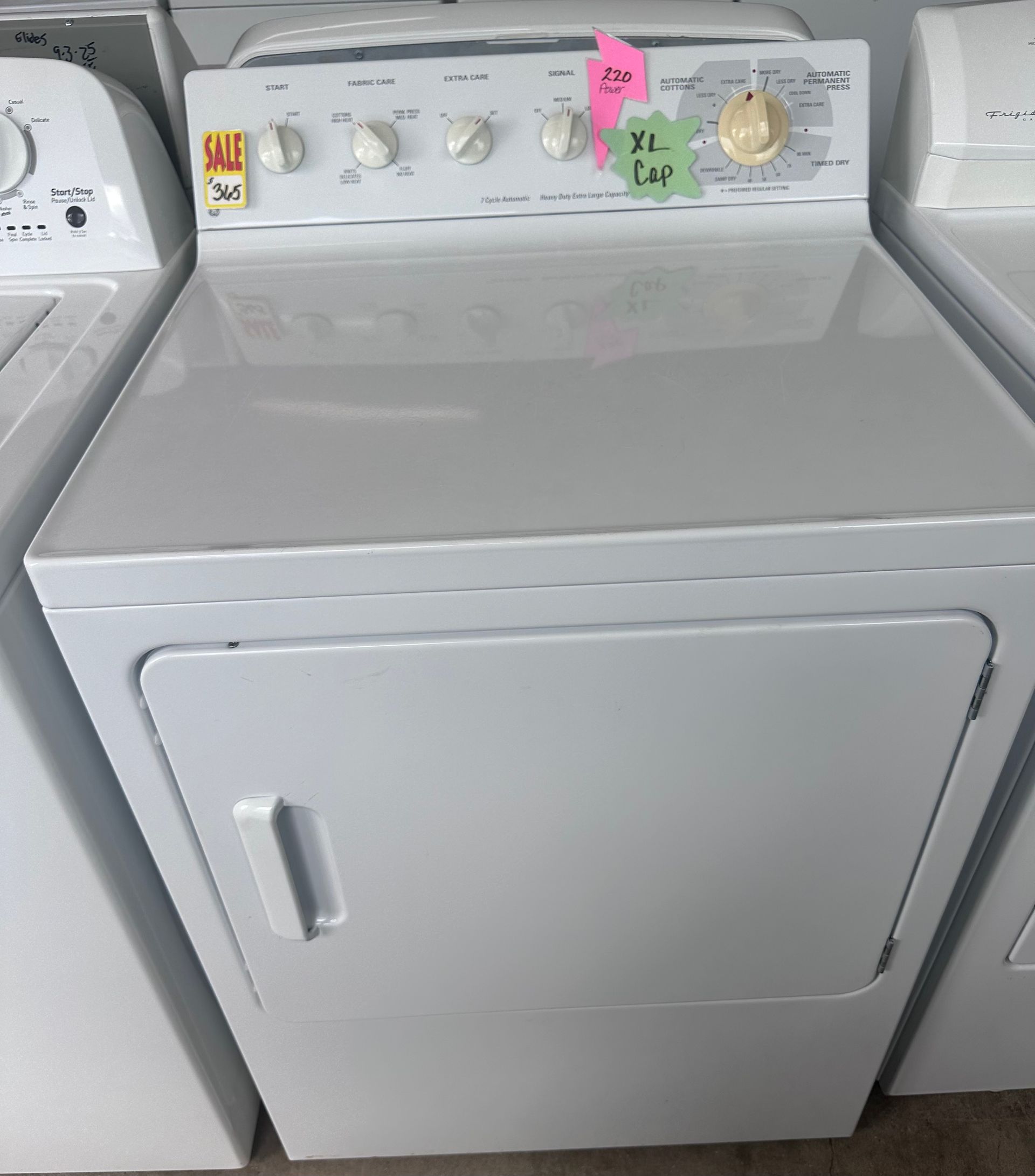White clothes dryer with top controls, in a store setting.
