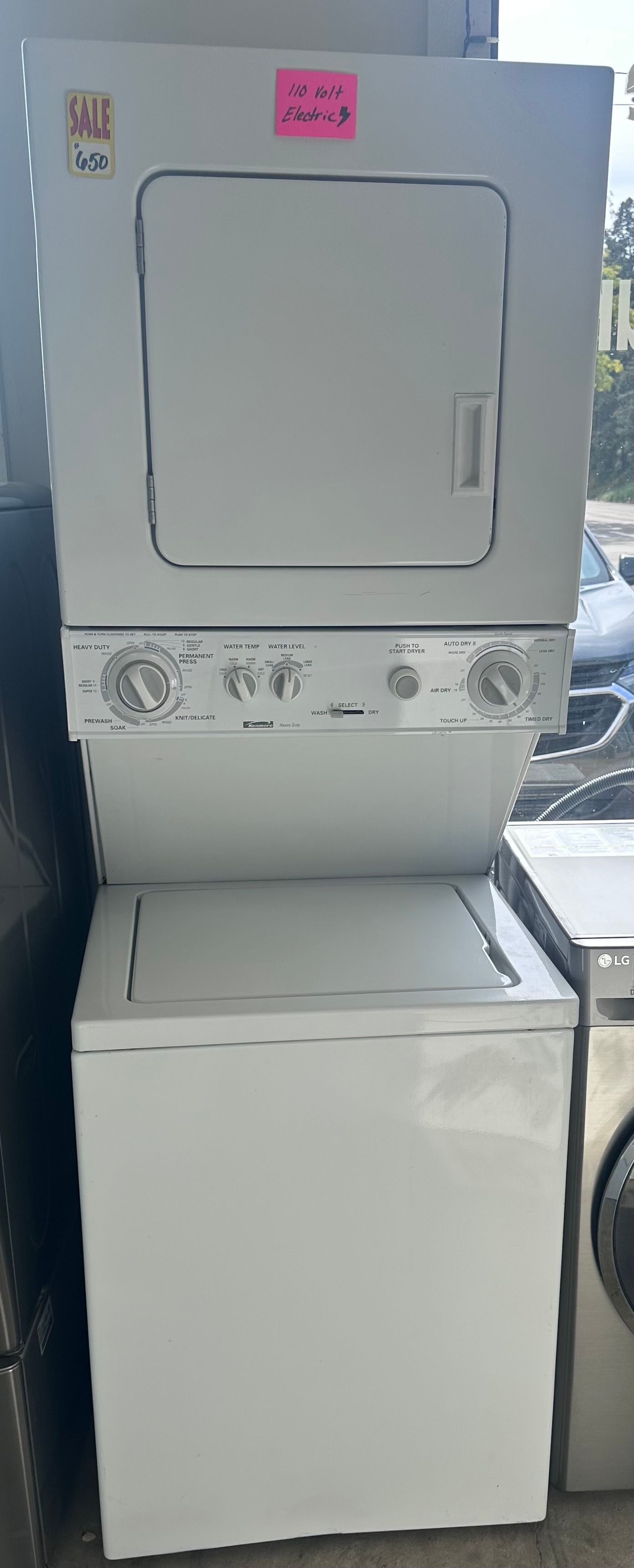 Stacked white washer and dryer unit, possibly in a store. Pink sale sticker on top.