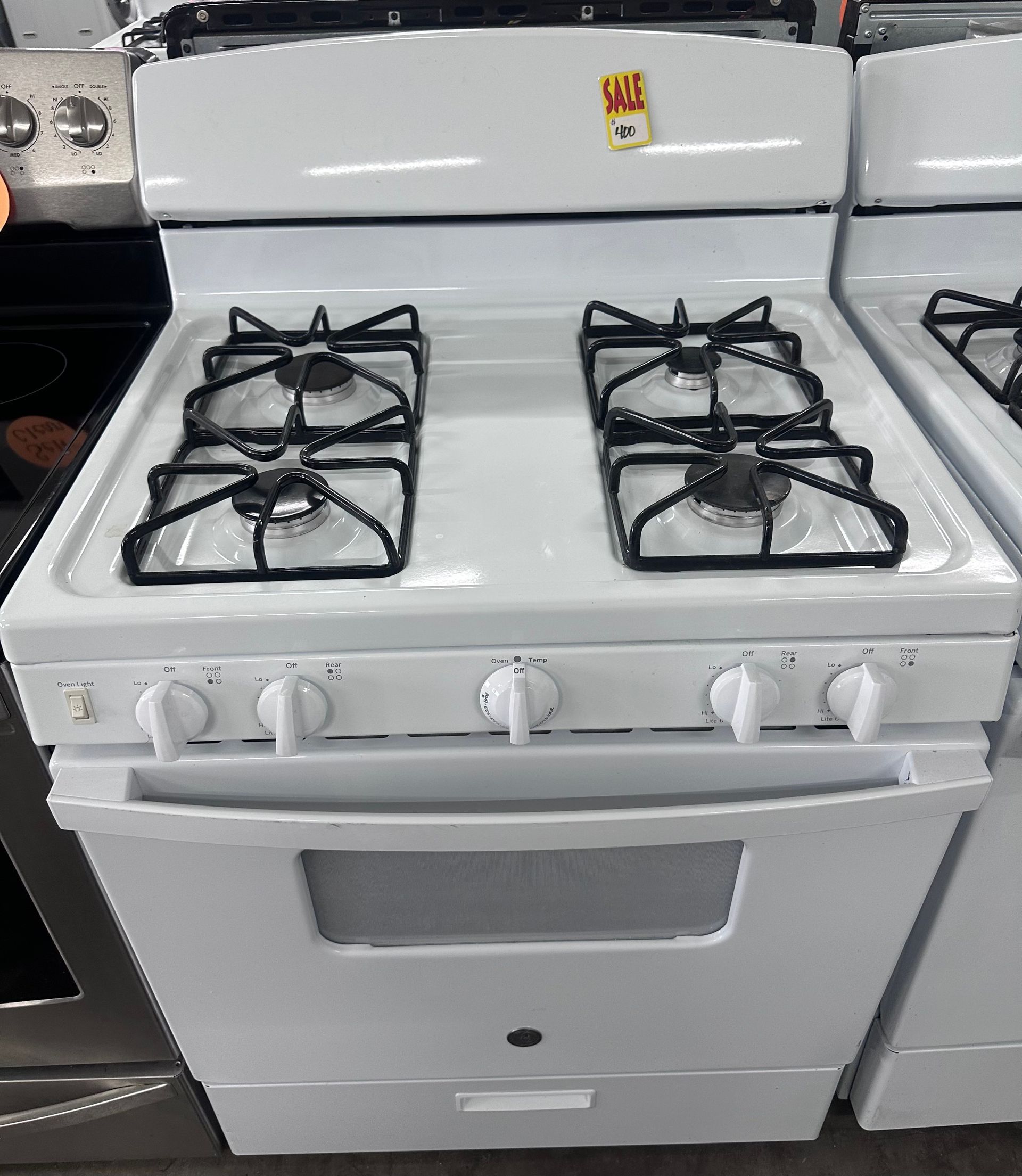 White gas stove with four burners and front control knobs in a kitchen.