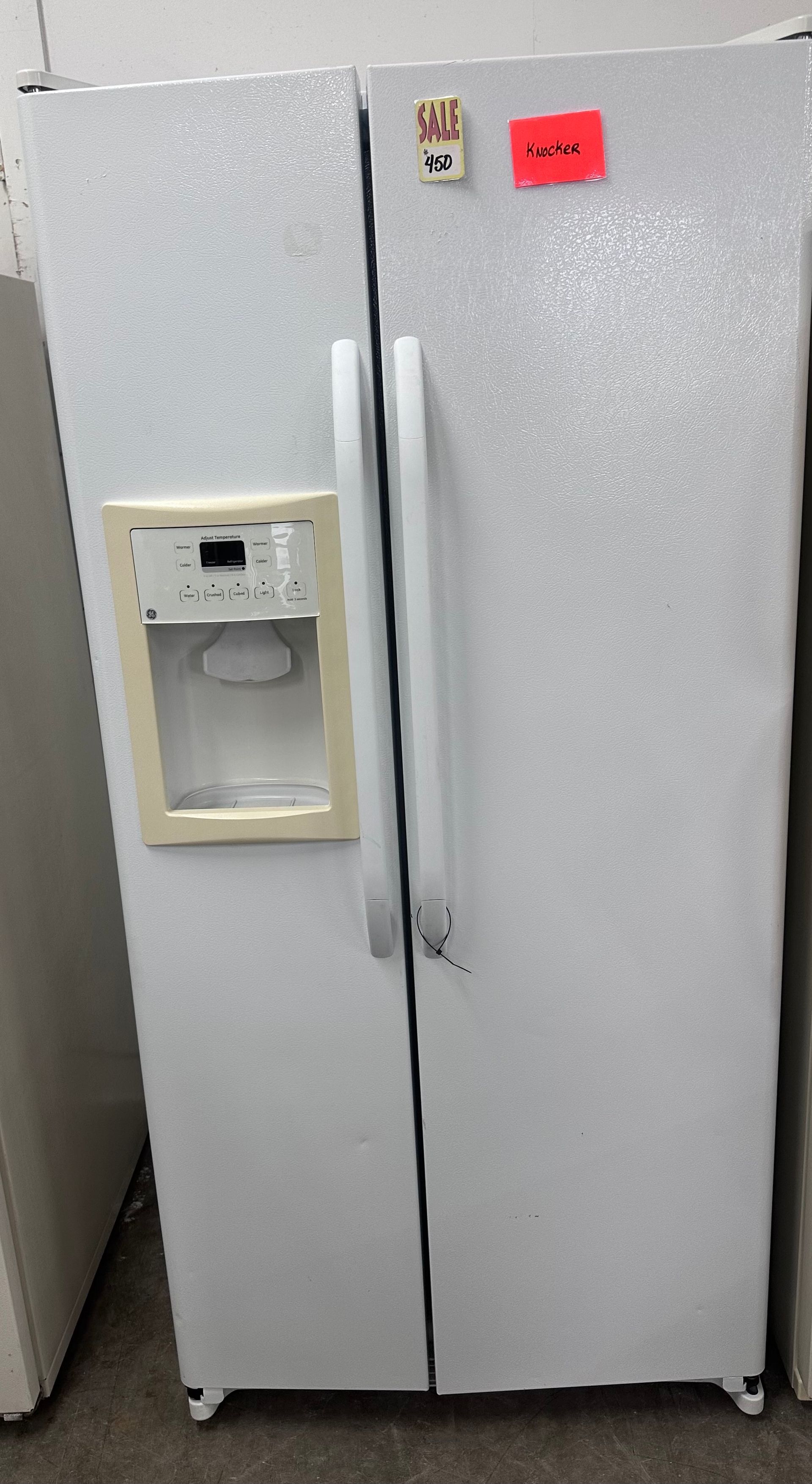 White side-by-side refrigerator with water dispenser and ice maker, standing in a kitchen.