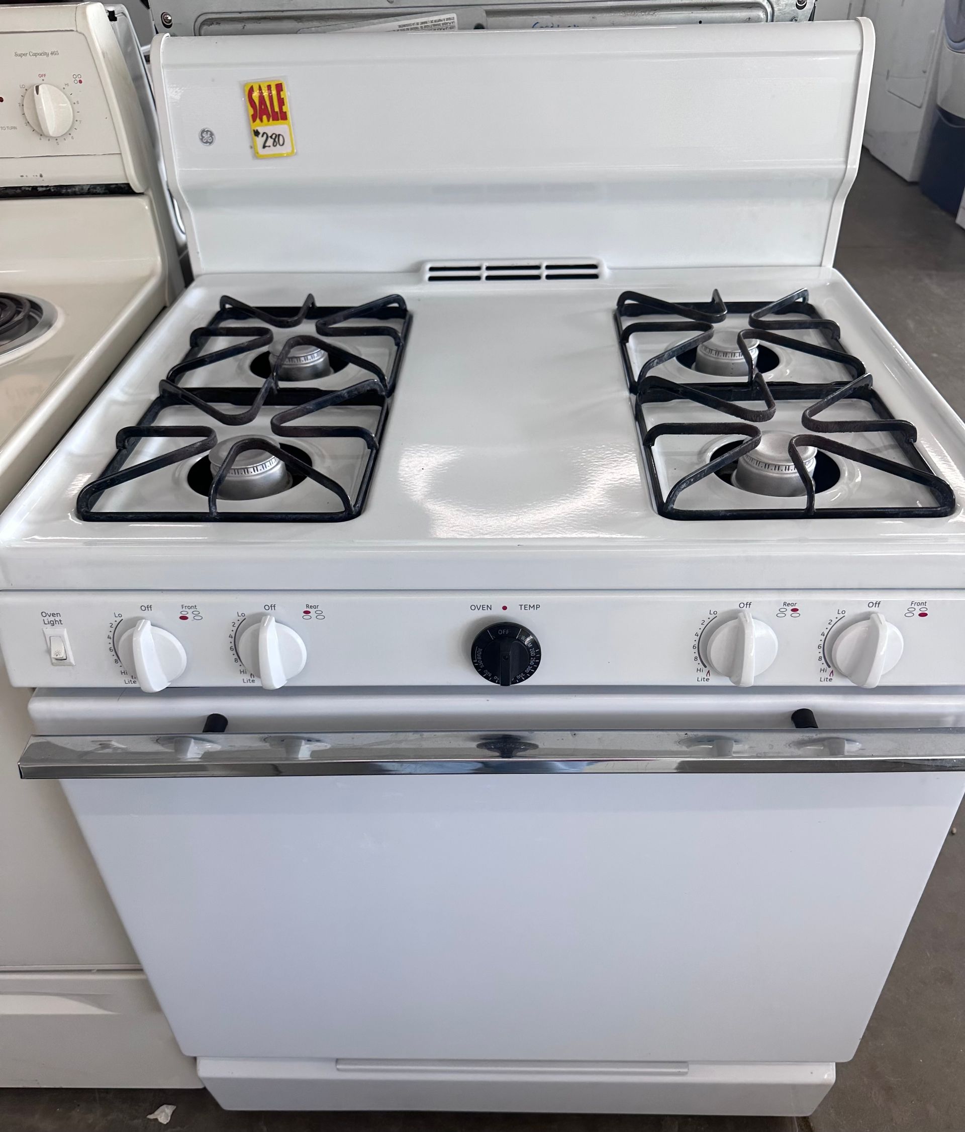 White gas range with four burners, oven below, control knobs, and stovetop grates.