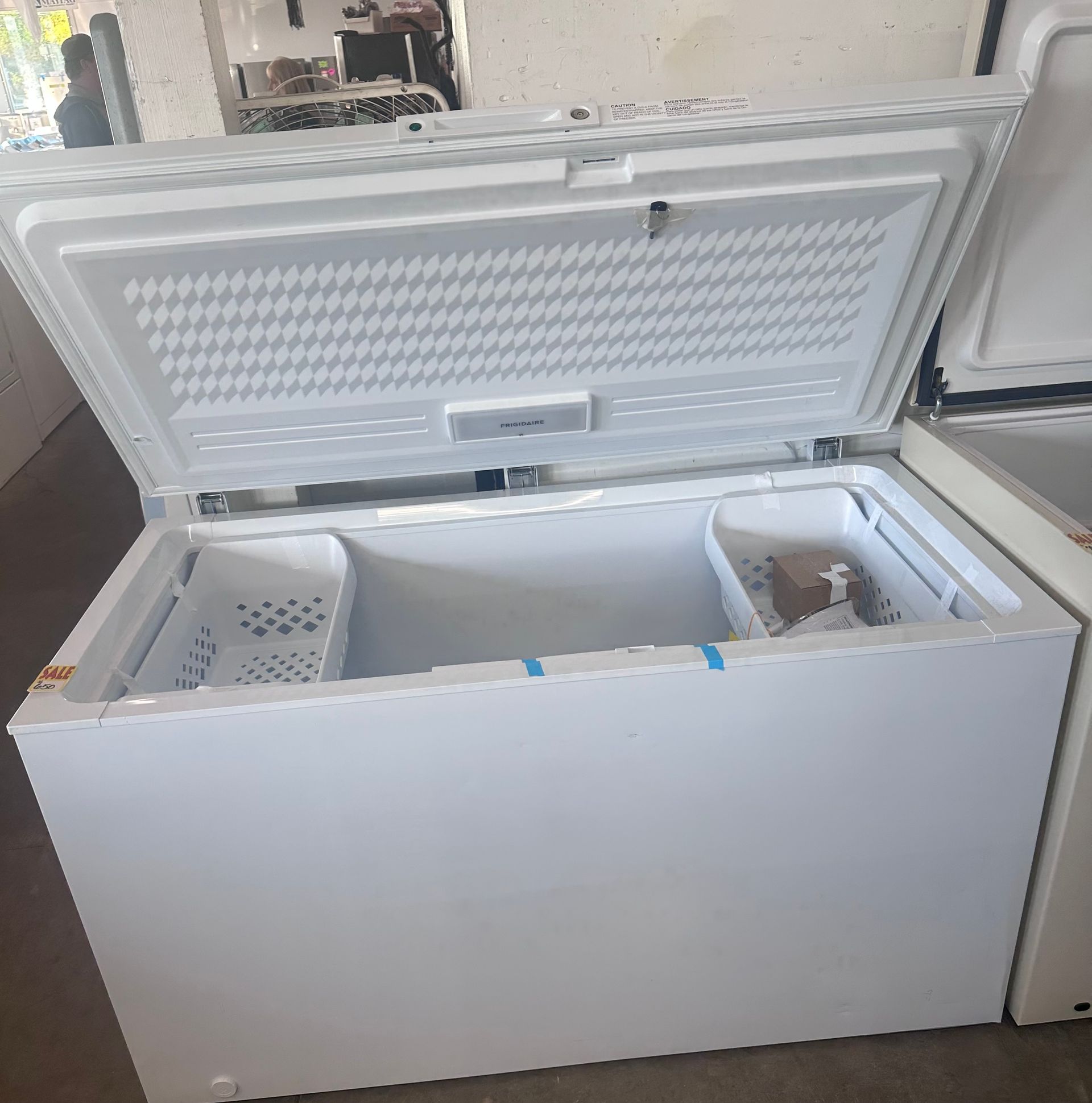 White chest freezer with lid open, two storage baskets visible.