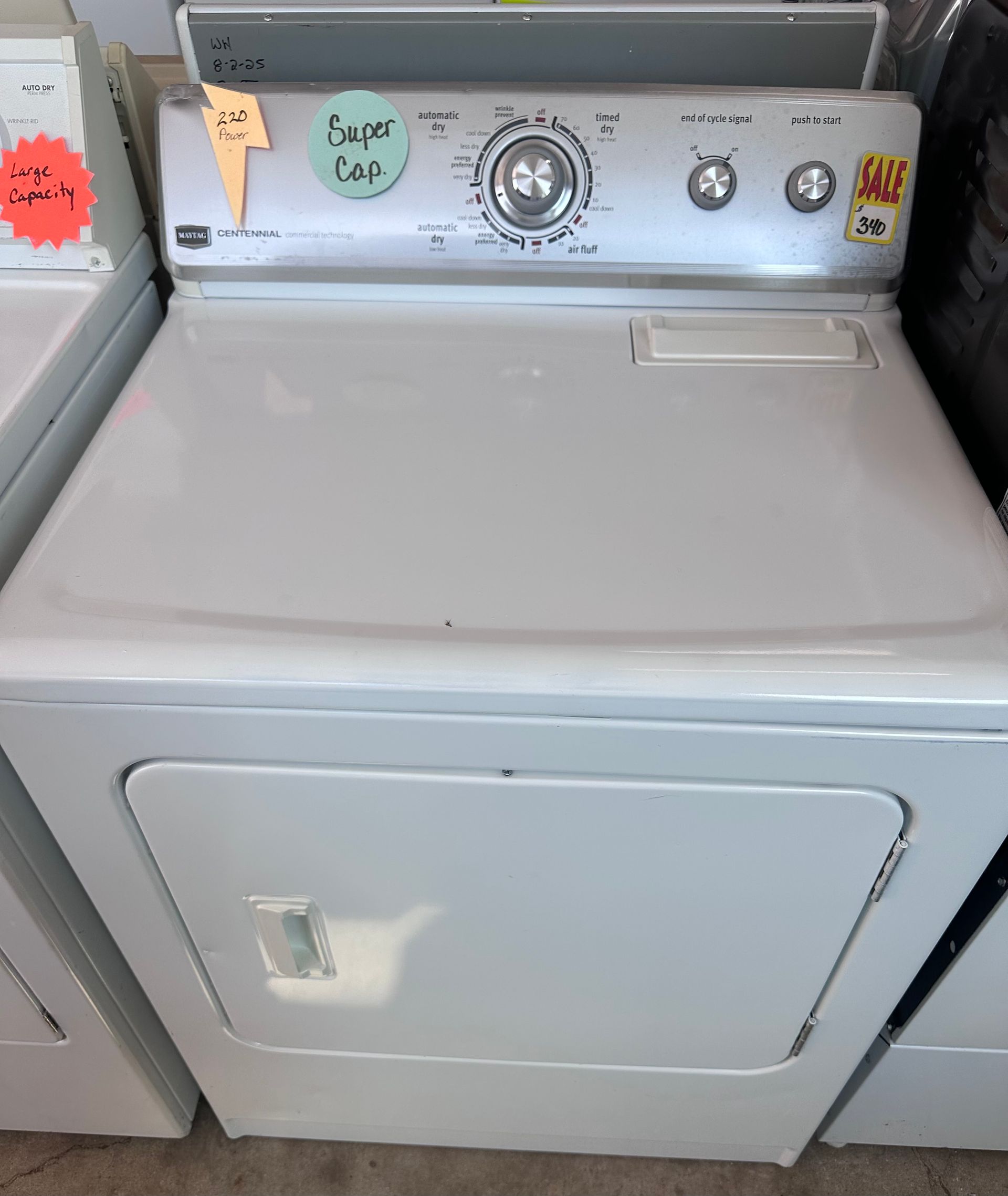 White Kenmore dryer with control panel, door, and price tags.