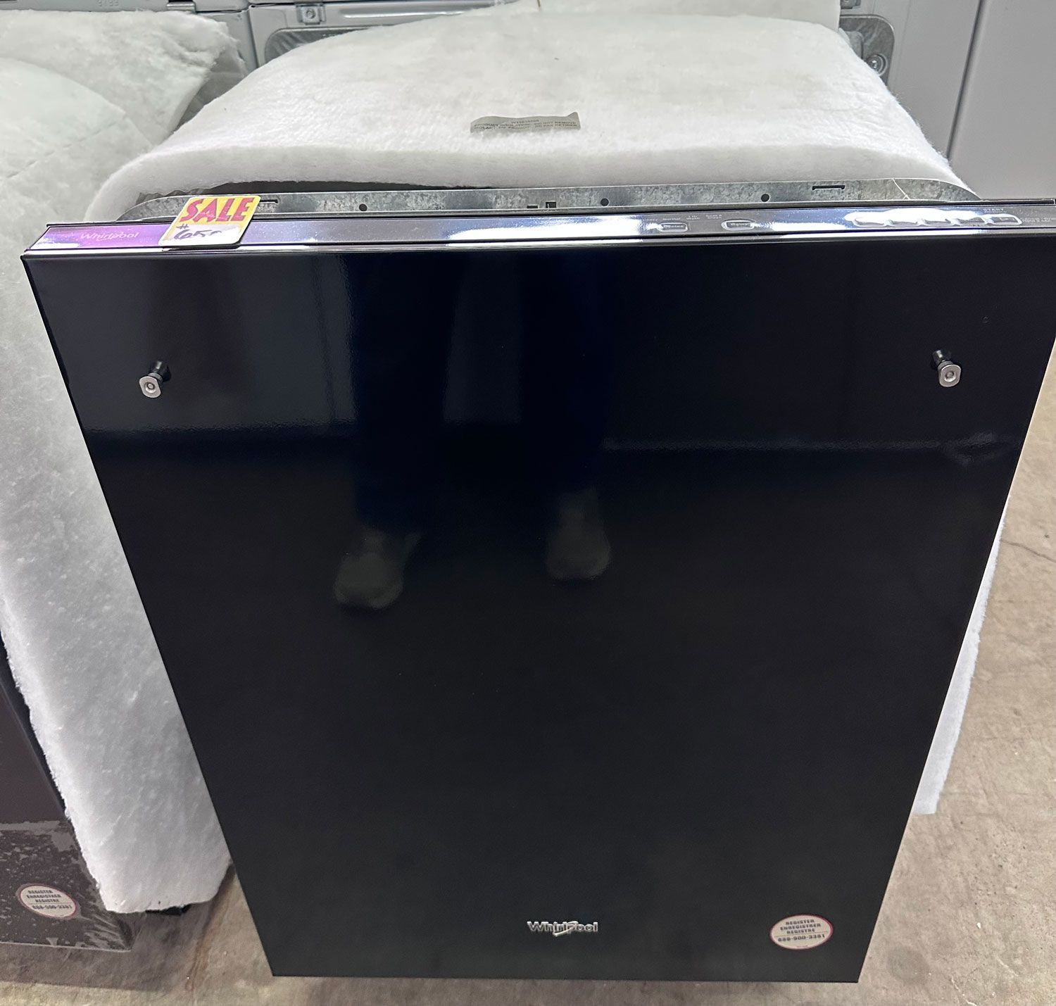 A black dishwasher with a polished, reflective finish and a sales tag, positioned in a retail setting.