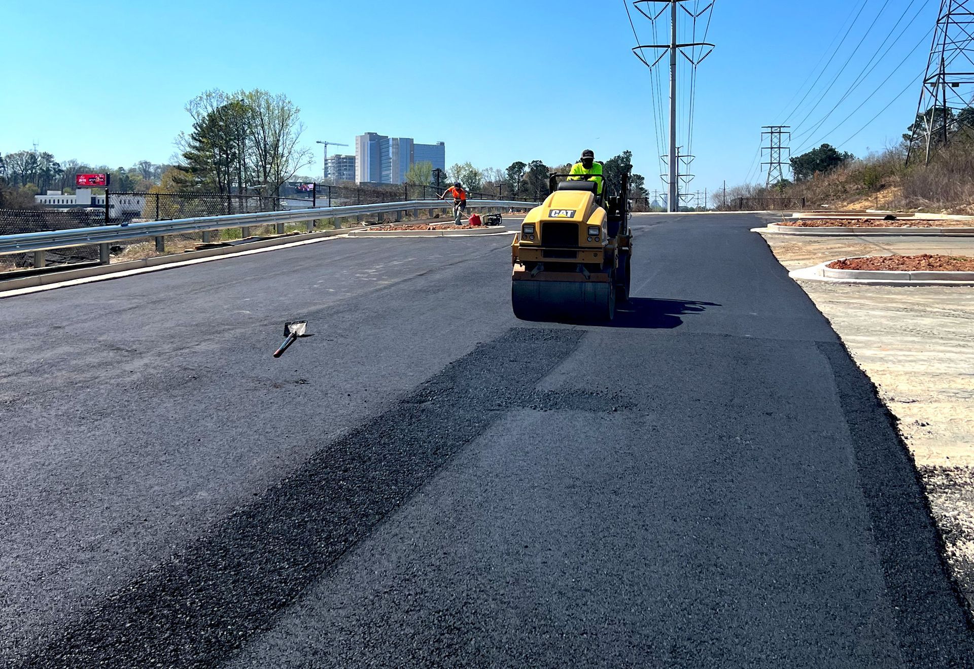 workers pouring asphalt on pavement being constructed
