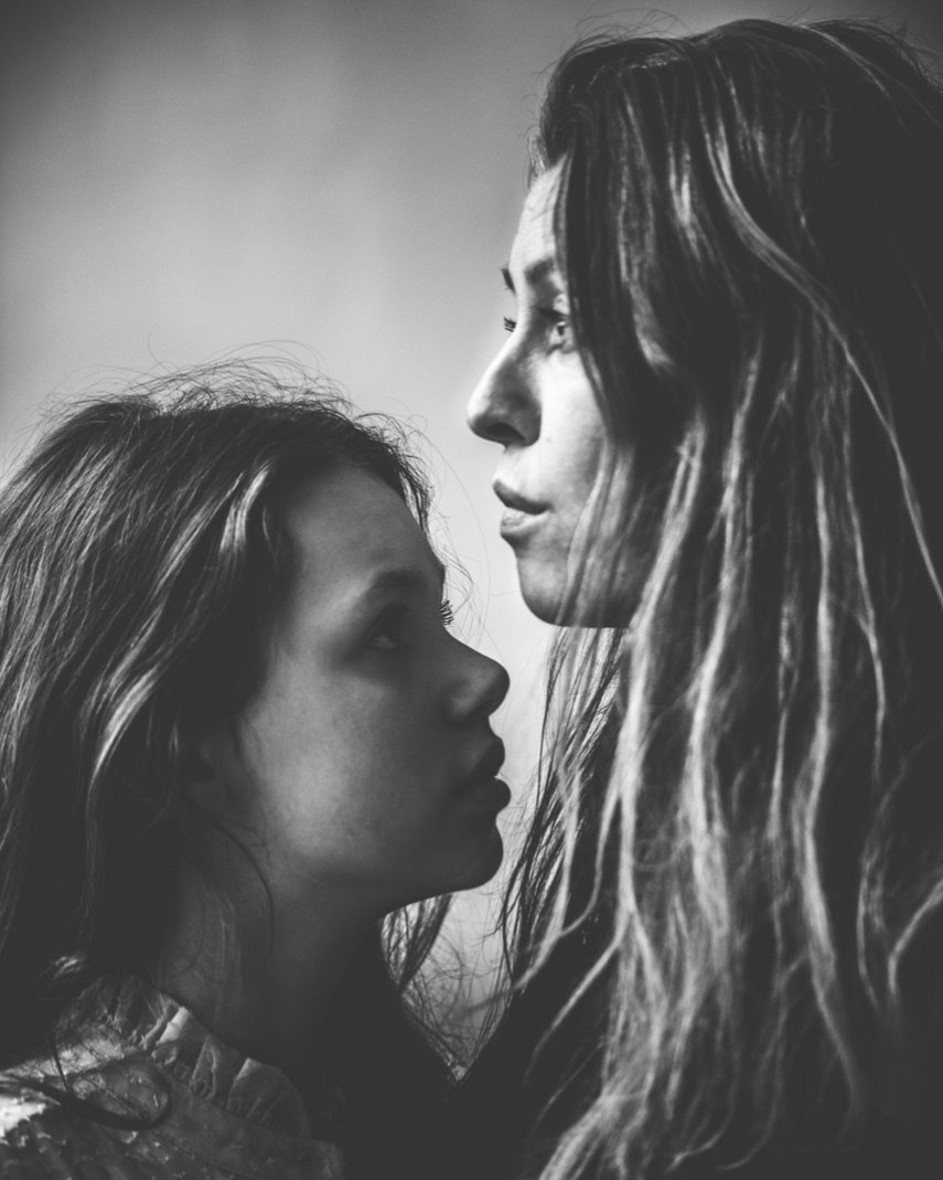 Twee vrouwen staan ​​dicht tegenover elkaar, in zwart-wit. De ene kijkt naar beneden, de andere naar voren.