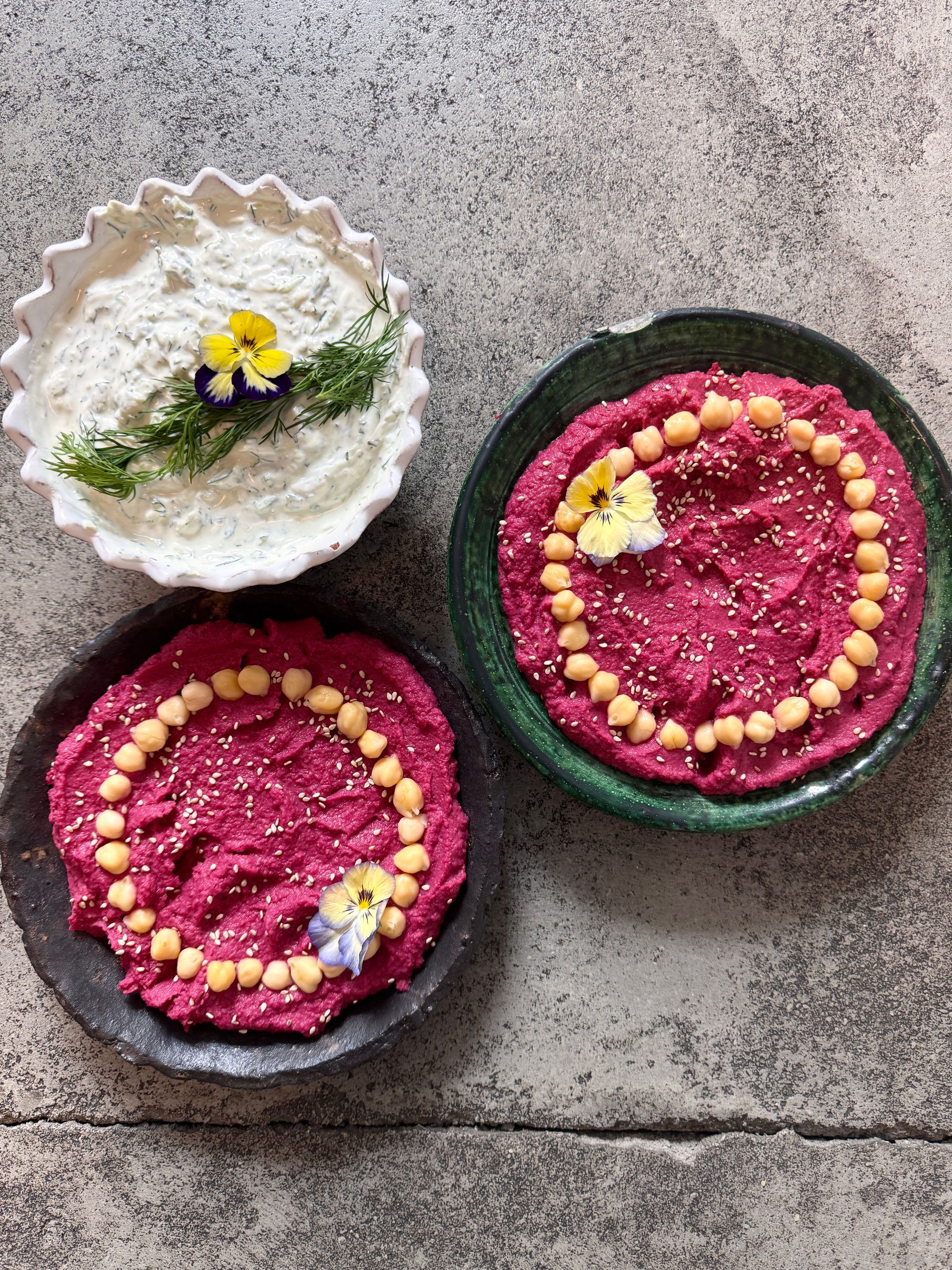 Drie dipsauzen: bietenhummus met kikkererwten en witte dip met dille. Gegarneerd met bloemen.