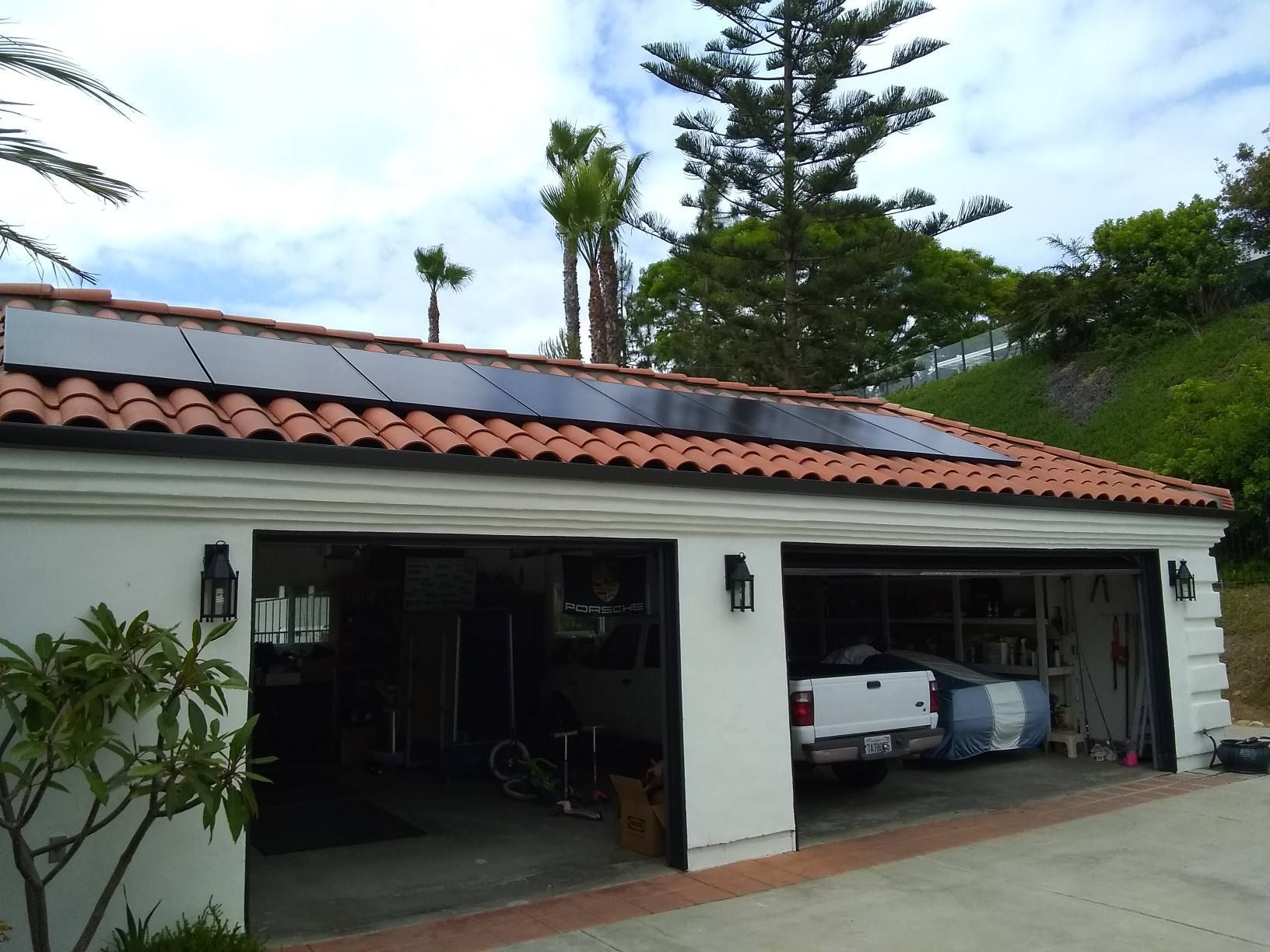 A car is parked in a garage with solar panels on the roof