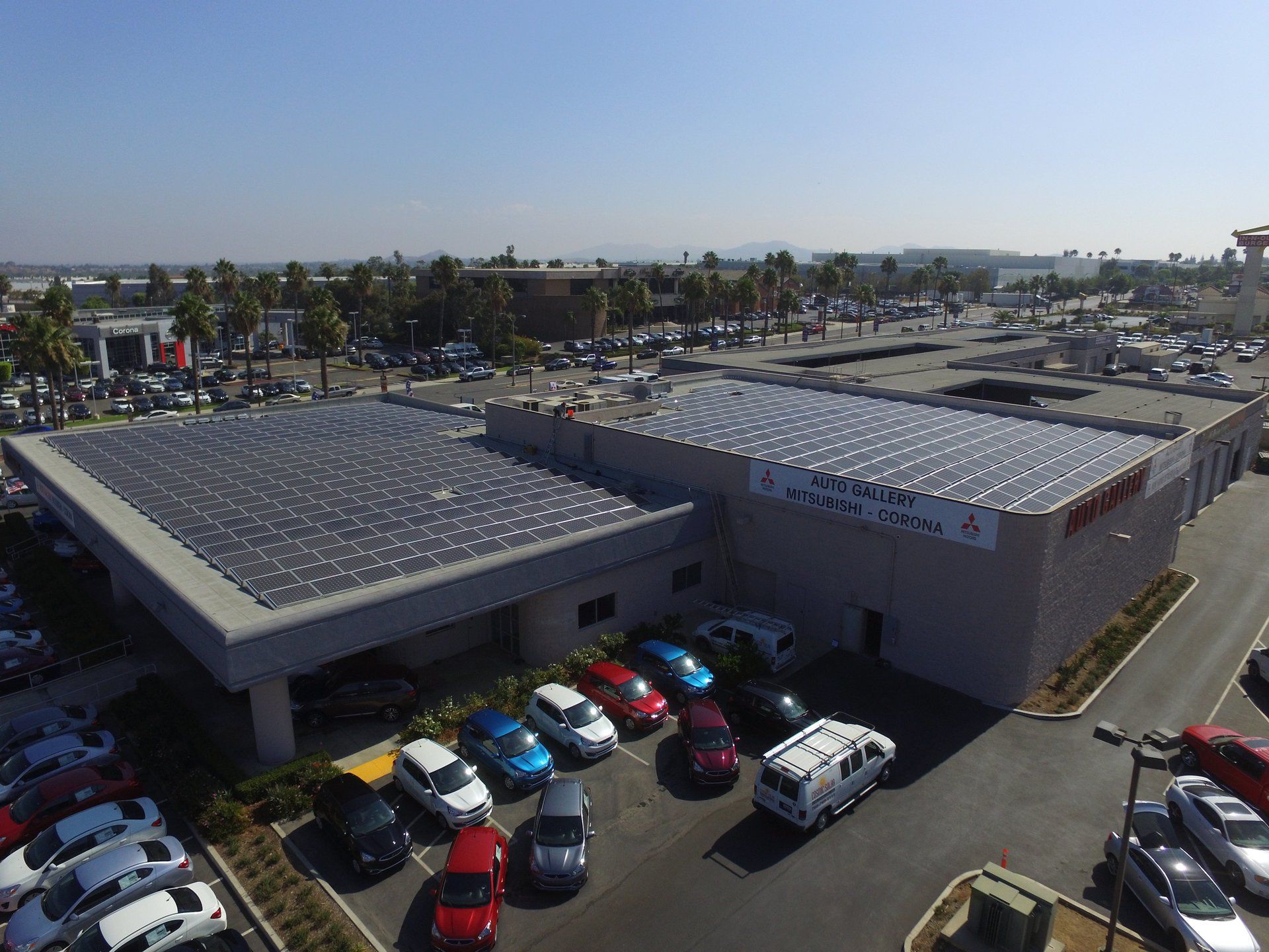 An aerial view of a car dealership with solar panels on the roof