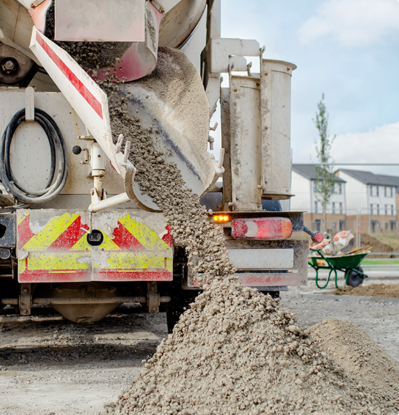 A concrete mixer truck is pouring concrete into a wheelbarrow.