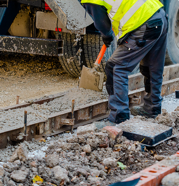A man wearing a yellow vest is using a shovel on a construction site