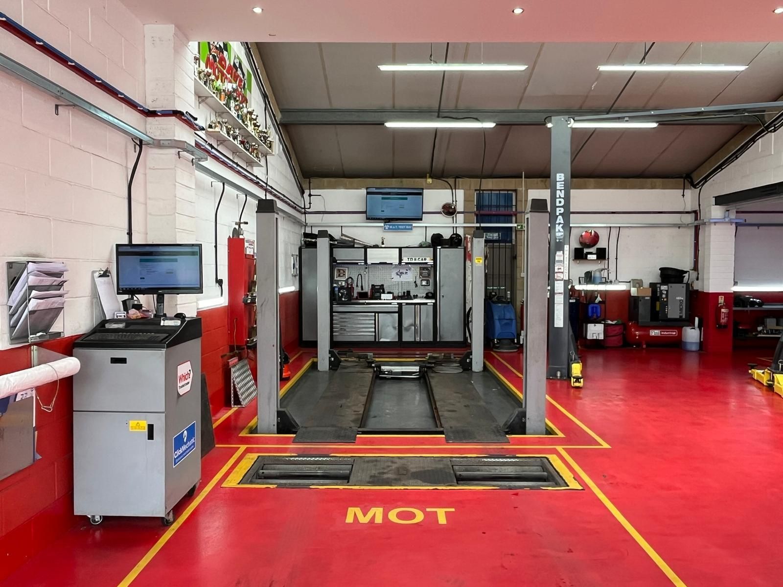 A garage with a red floor and a yellow line that says mot